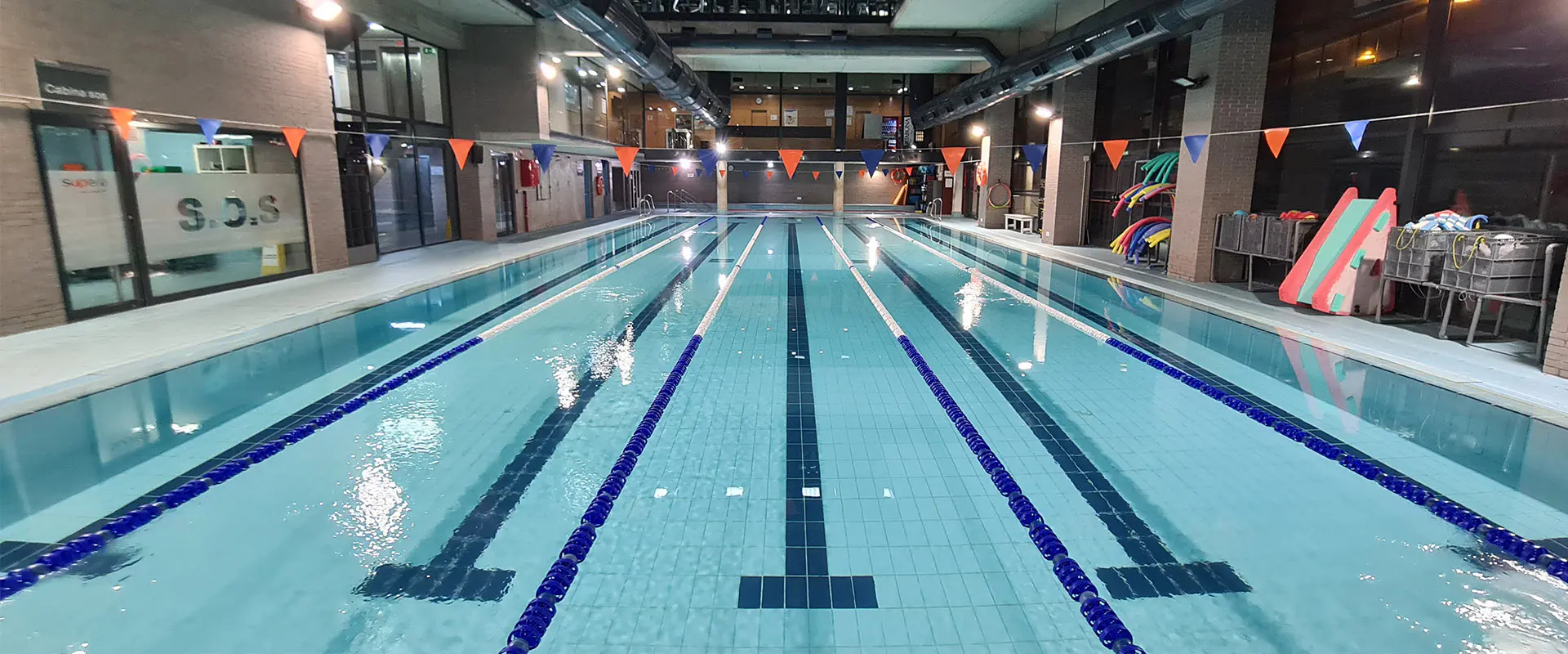 Panorámica frontal de la piscina de entrenamiento climatizada, con vista de las calles y la sala de socorrismo a la izquierda
