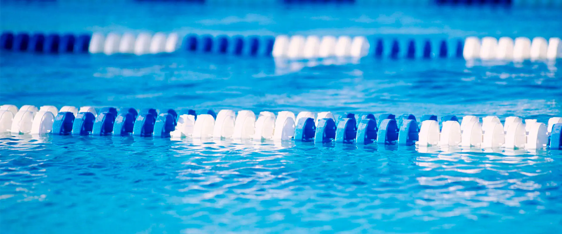Vista parcial de una piscina con agua, con detalle de las cuerdas divisoras de calles