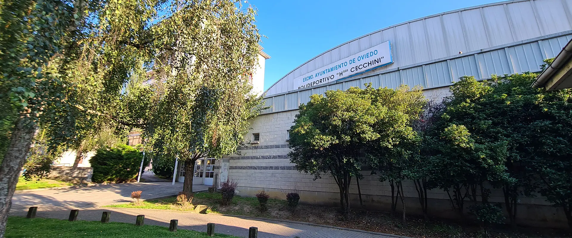 Fachada del polideportivo. Cartel con el nombre de la instalación altura del techo metálico en letras celestes y negras