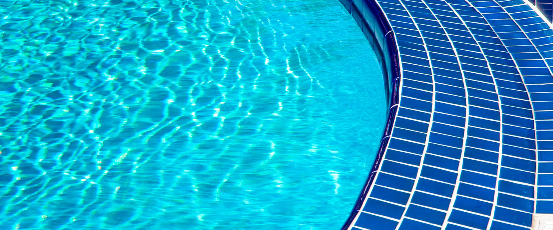 Vista parcial de una piscina con agua, con detalle del suelo de azulejo