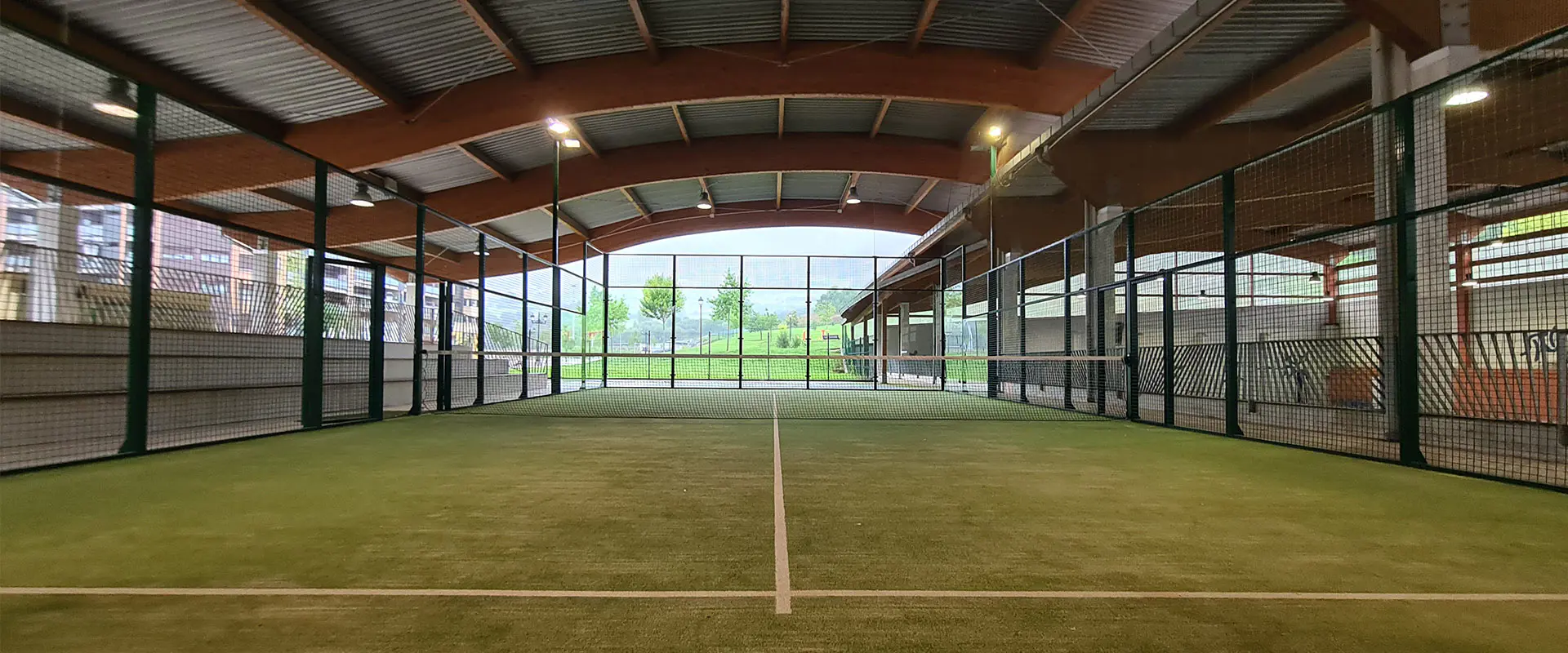 Pista de pádel cubierta de hierba sintética. Vallas de cierre. Cubierta ondulada de vigas de madera