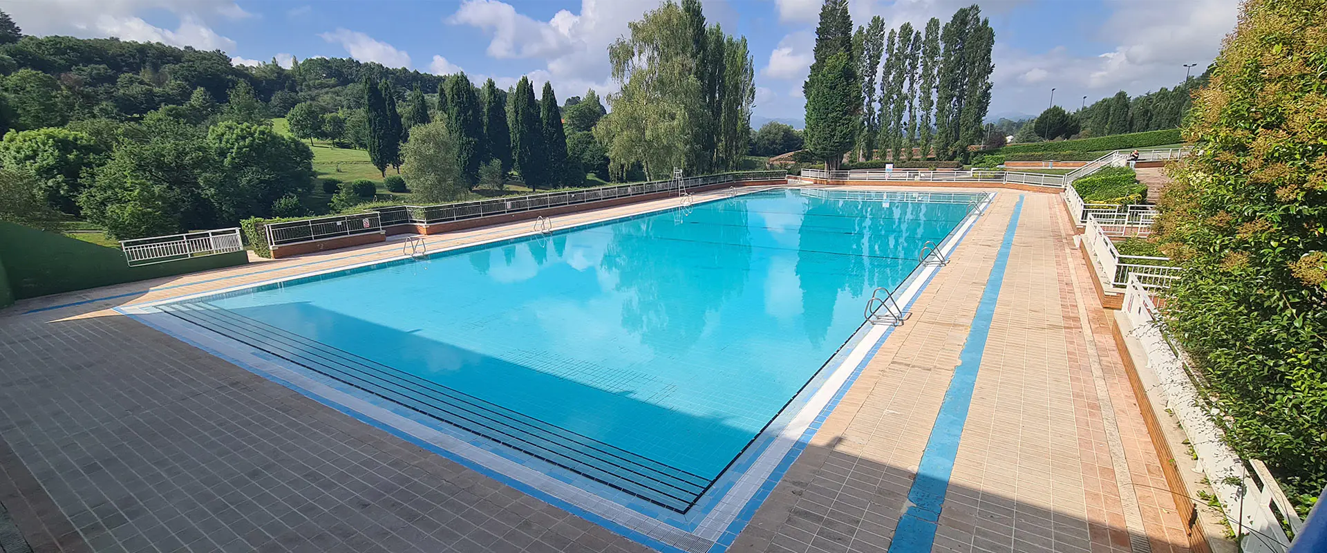 Piscina principal de San Lázaro. Rodeada de vegetación. Vistas al Parque de Invierno