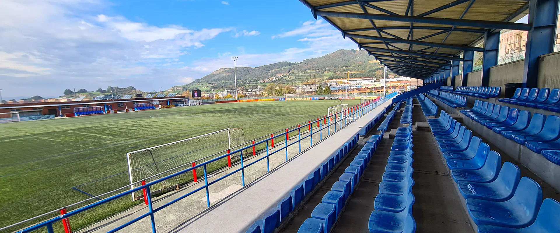 Vista del campo de fútbol desde las gradas cubiertas, con detalle de las butacas y una portería
