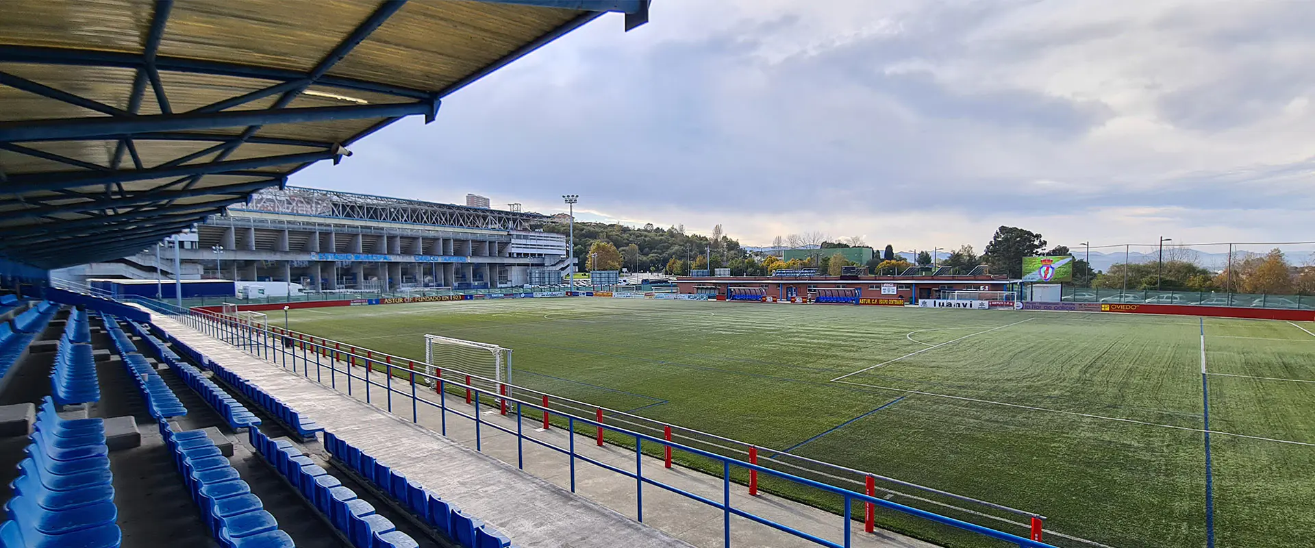 Vista del campo desde la grada cubierta lateral. Hileras hileras de butacas. Barandilla inferior