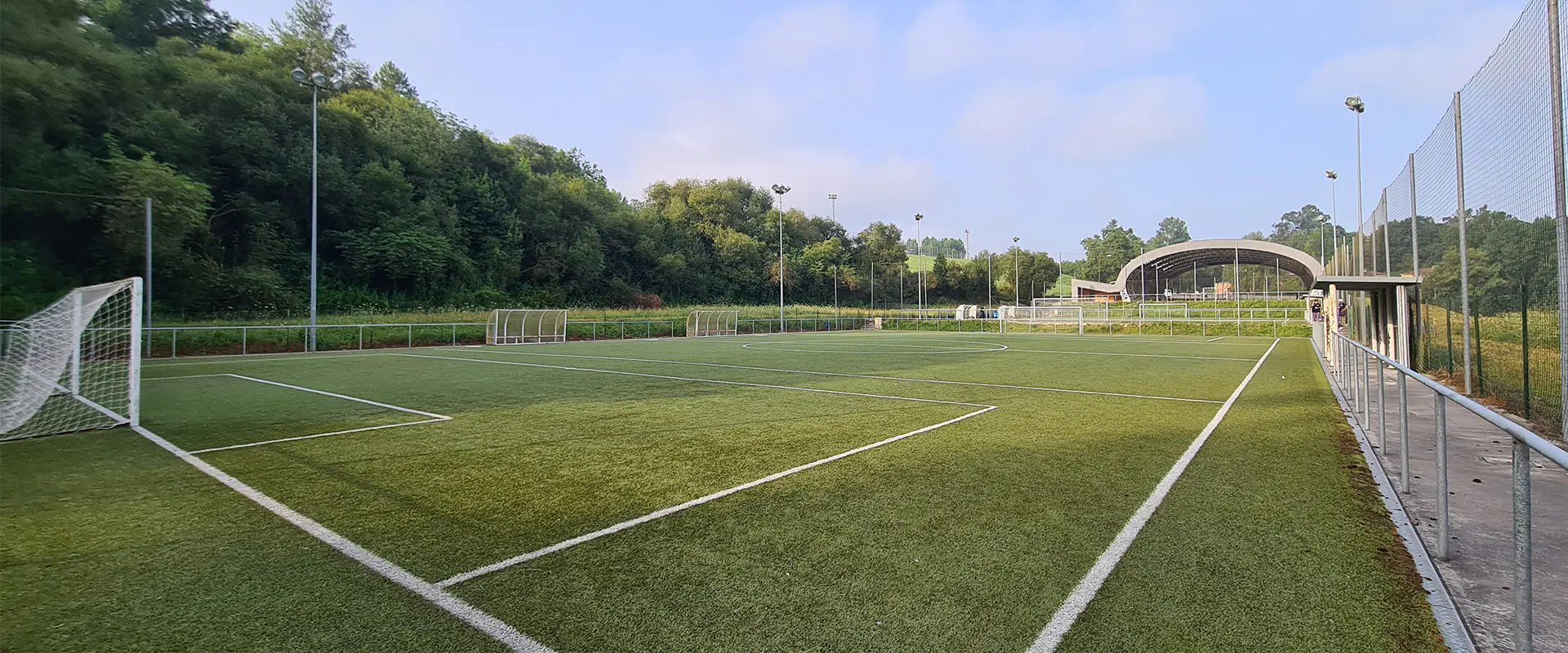 Panorámica de uno de los campos de fútbol 8 desde uno de los córneres, con las porterías y la pista polideportiva al fondo