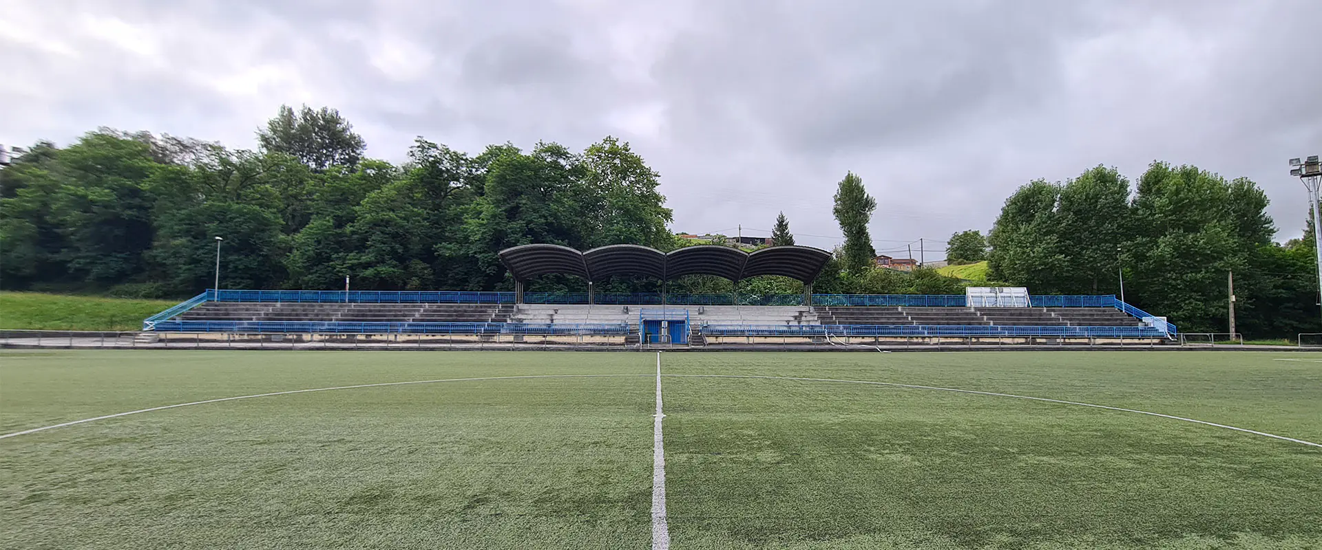 Vista frontal a pie de campo del terreno de juego, con la línea central y las gradas al fondo