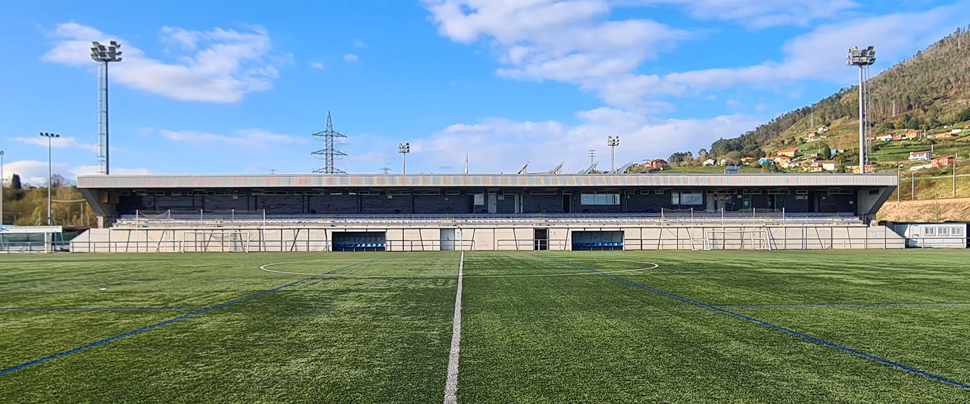 Terreno de juego a pie de campo. Línea blanca divisoria central. Gradas al fondo