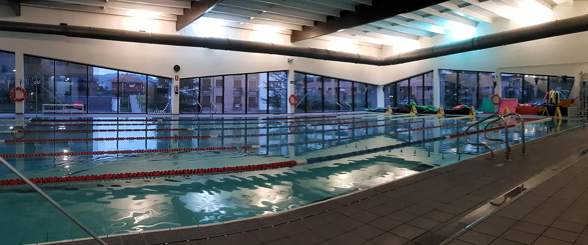 Panorámica lateral de la piscina de nado, rodeada de amplios ventanales con vistas al exterior