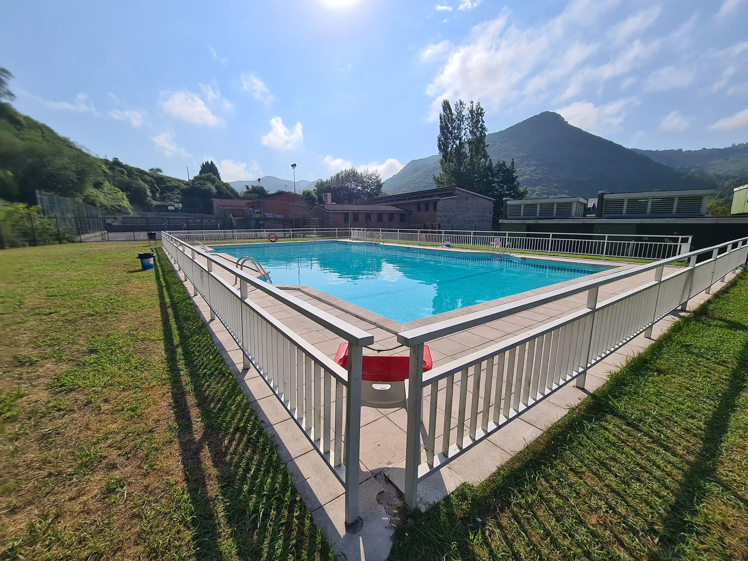 Vista del vaso de la piscina desde una esquina, con el edificio de servicios a su derecha