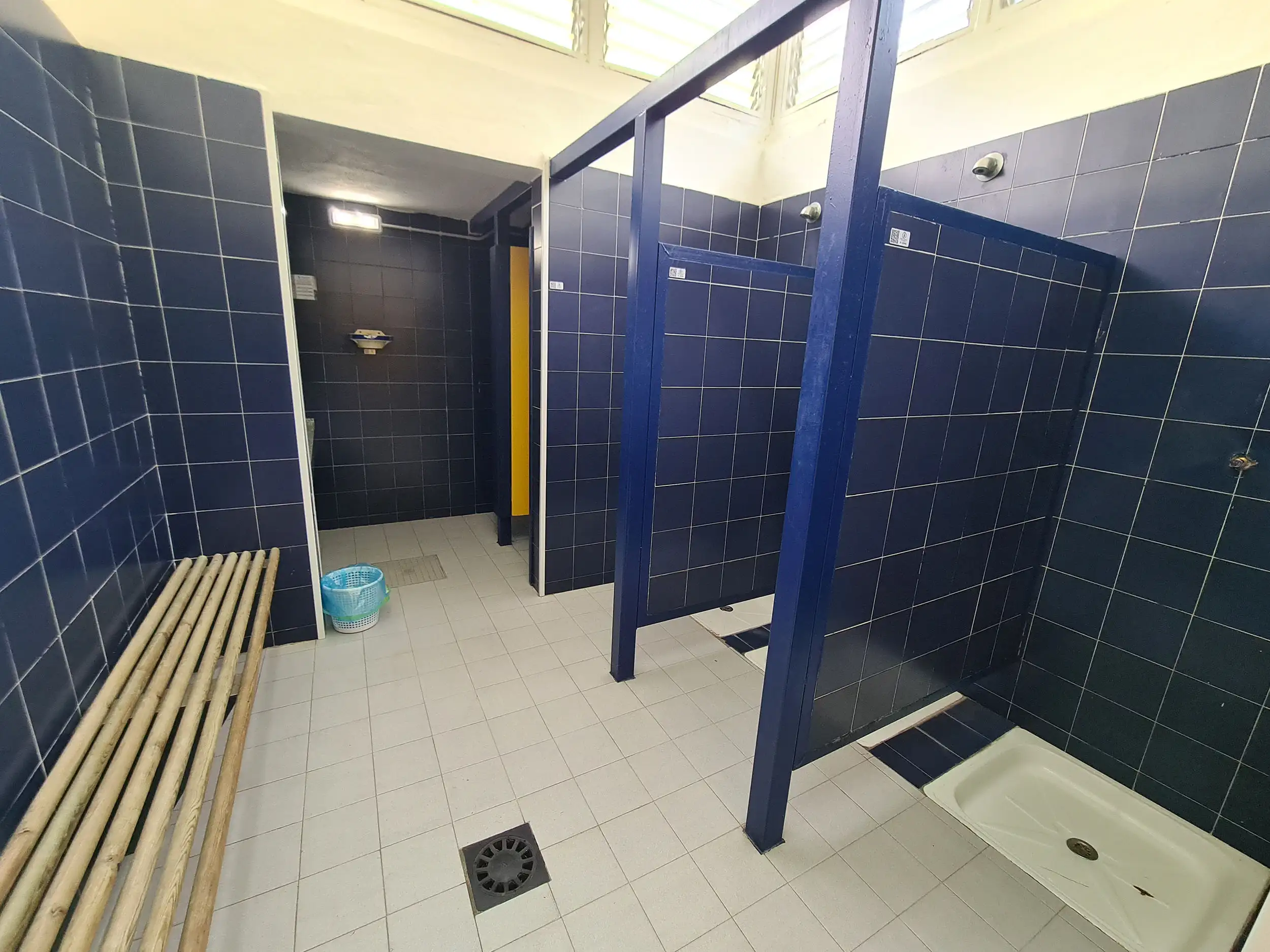 vista de un vestuario con banco, duchas y aseos