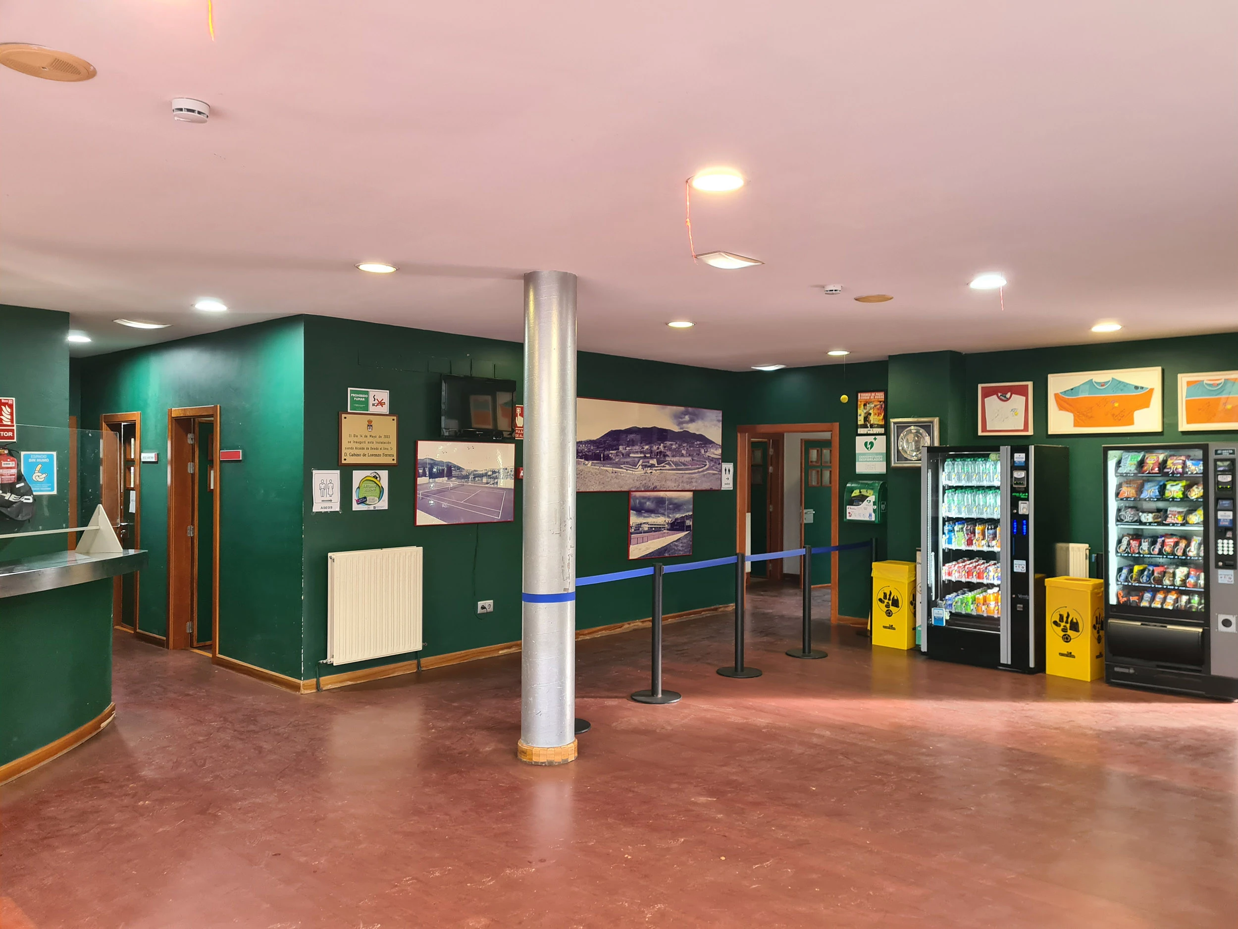 Área de recepción, con el mostrador a la izquierda, máquinas expendedoras a la derecha y accesos al interior
