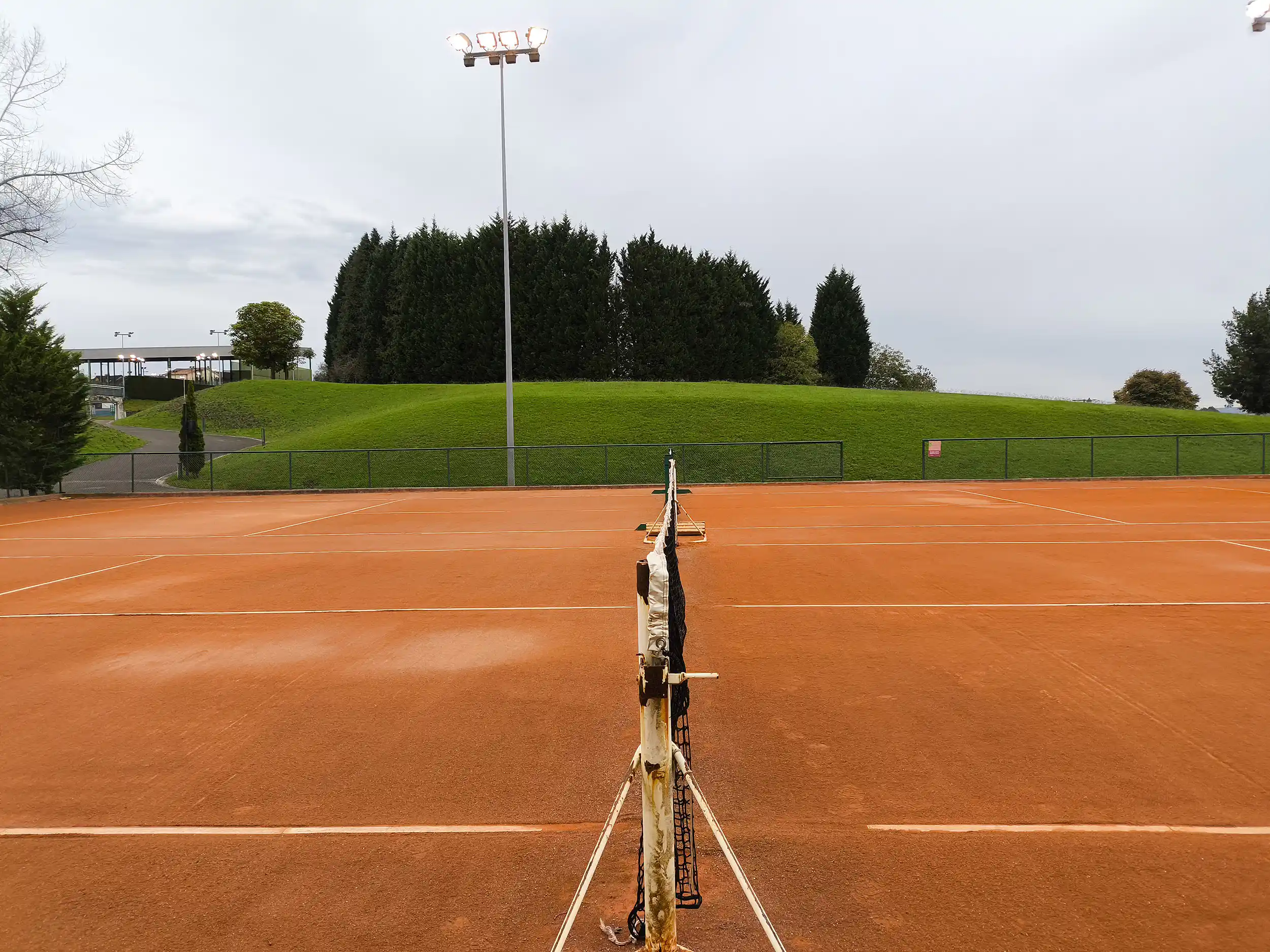 Lateral de una pista de tenis de tierra batida, con detalle de la red