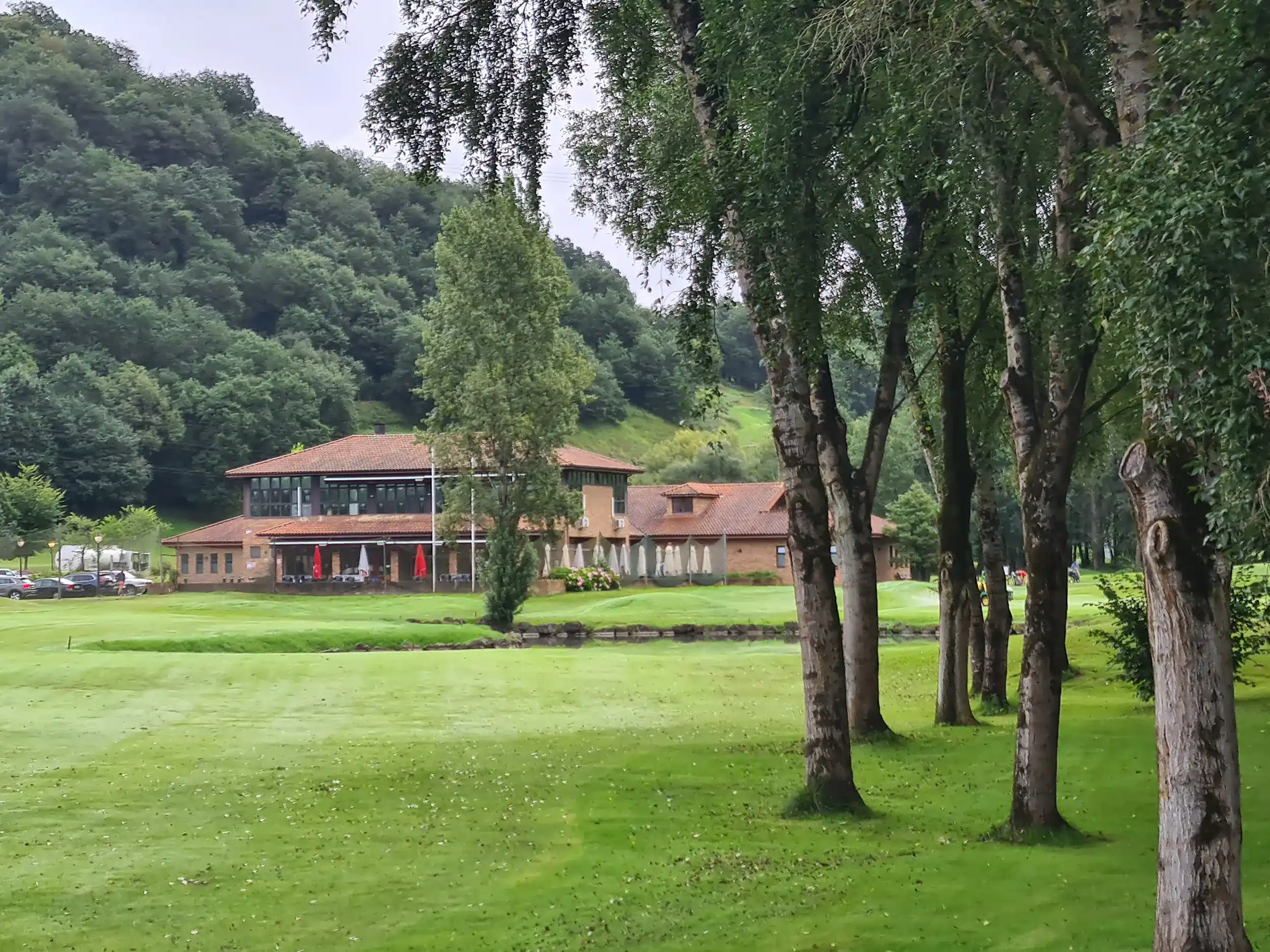 Edificio principal de visto desde los hoyos finales del campo en una zona con árboles y un lago