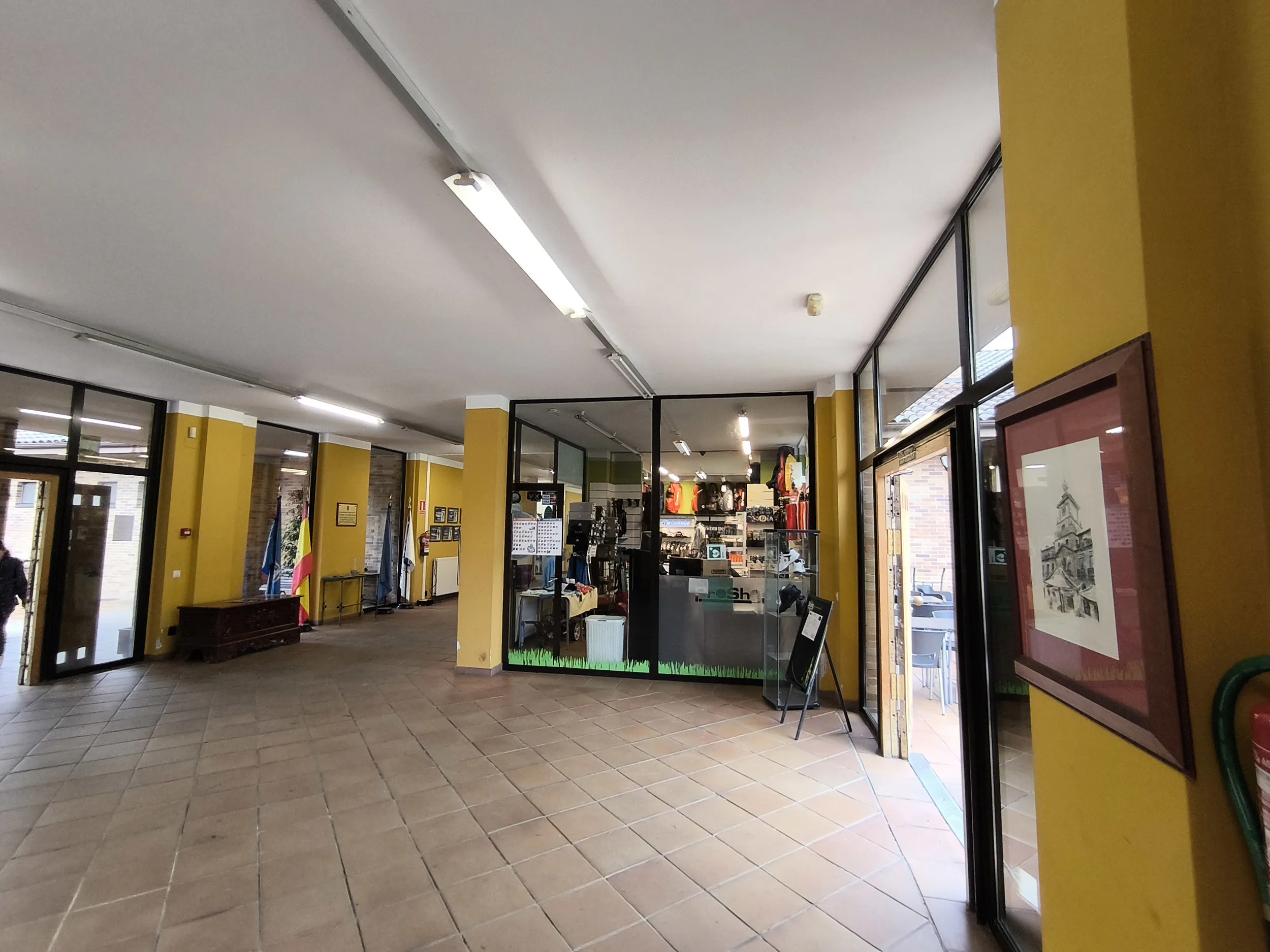 Vestíbulo, con el escaparate de una tienda de artículos de golf y una puerta de salida lateral a la terraza-restaurante