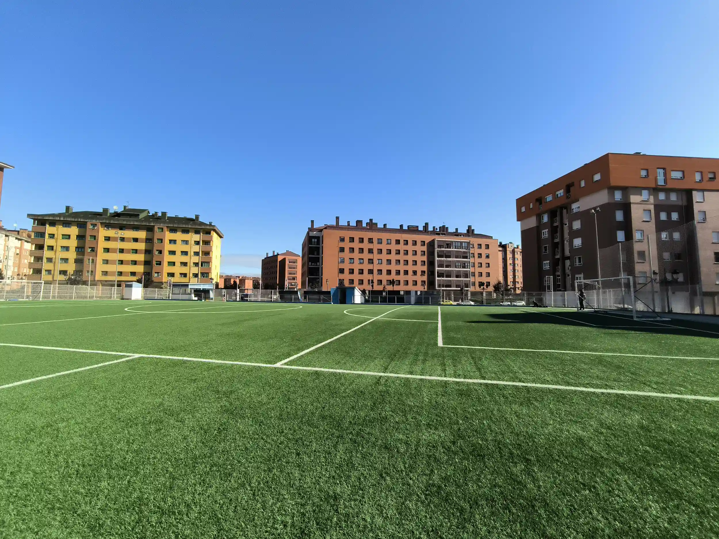Perspectiva lateral del campo de fútbol distinguiéndose las diferentes líneas blancas del césped y una de las porterías