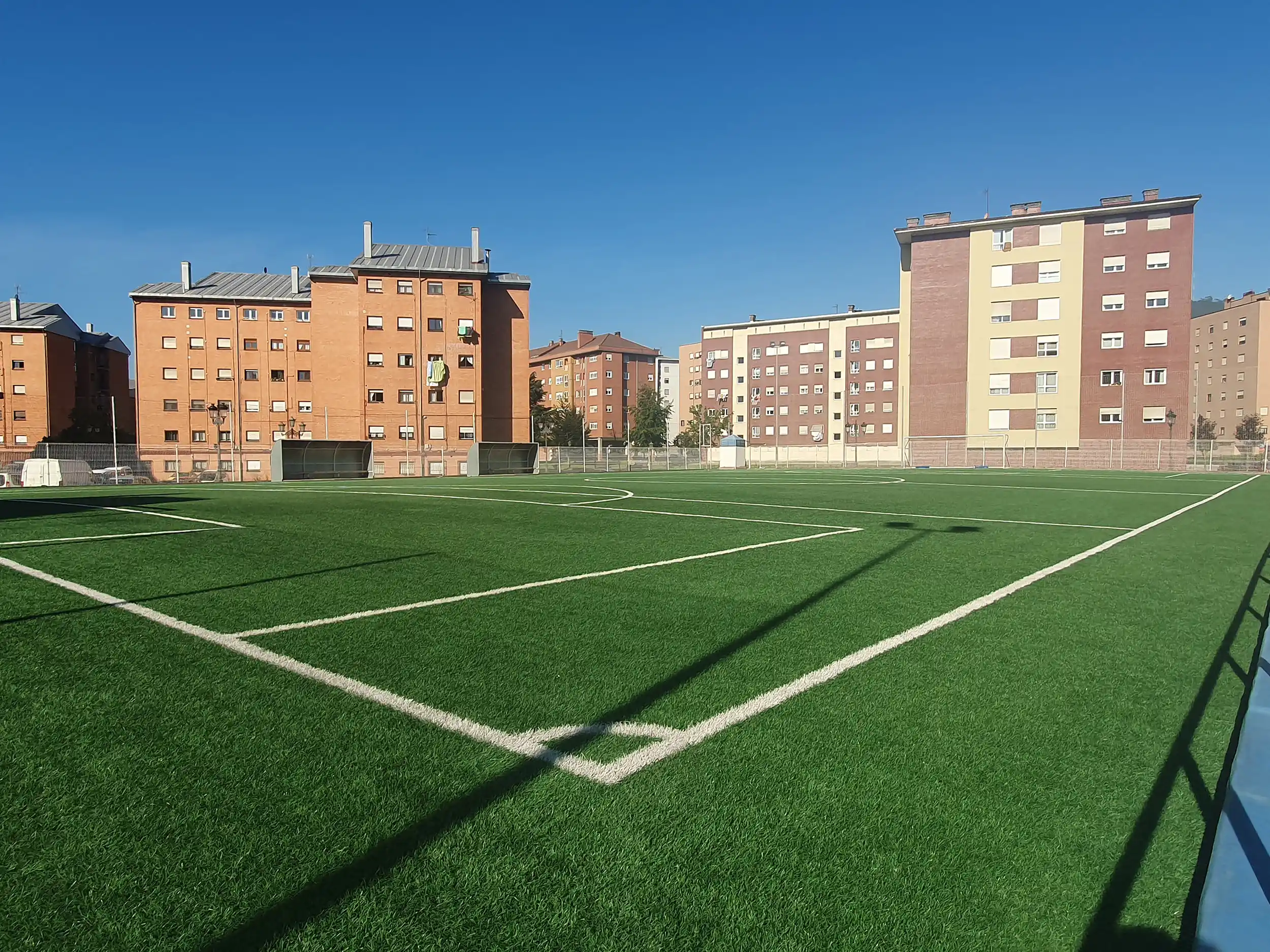 Campo de fútbol desde uno de los córneres, distinguiéndose la práctica totalidad del campo y los banquillos