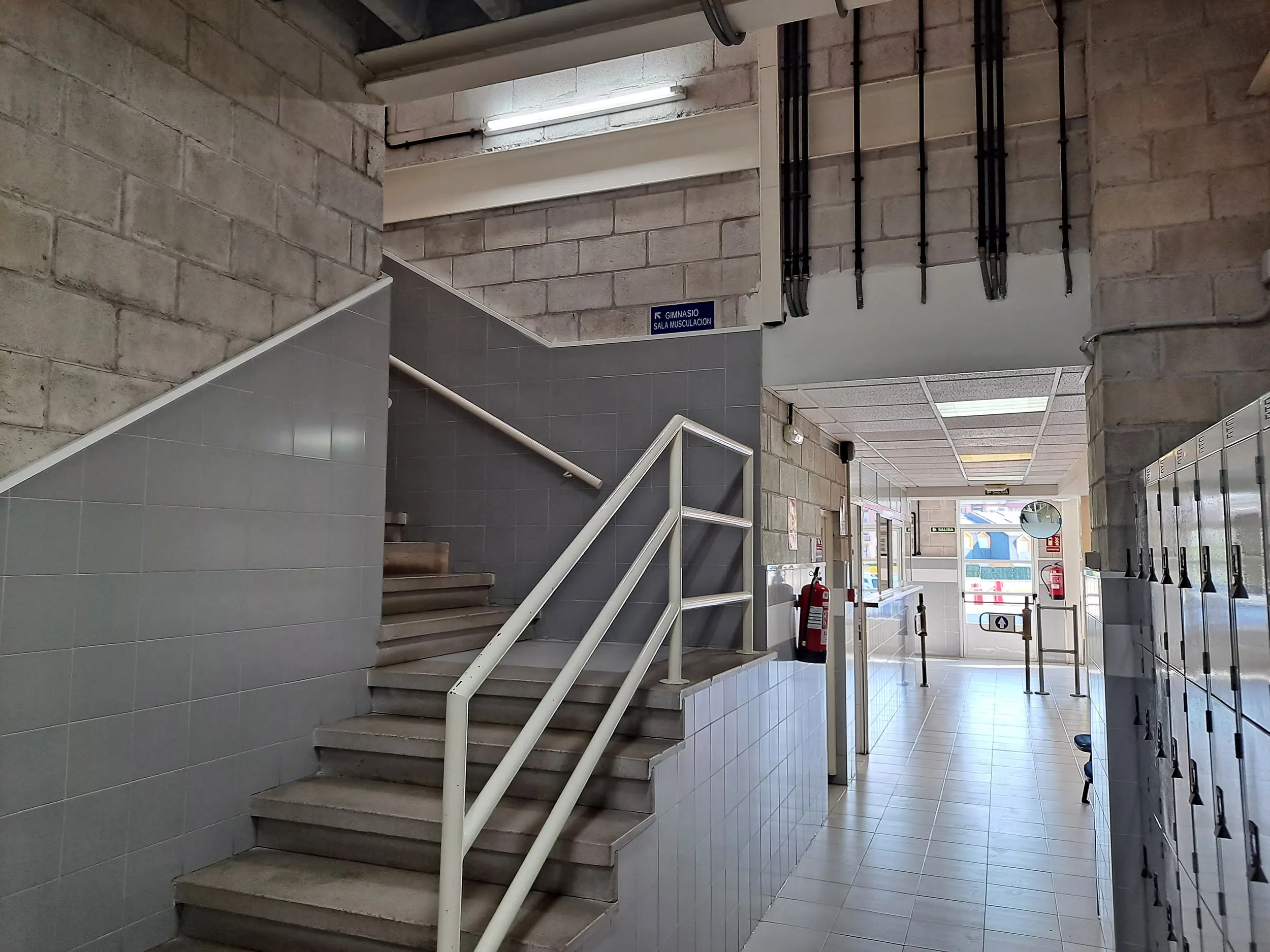 Escalera de acceso al piso superior. Pasillo de acceso a vestuarios y taquillas