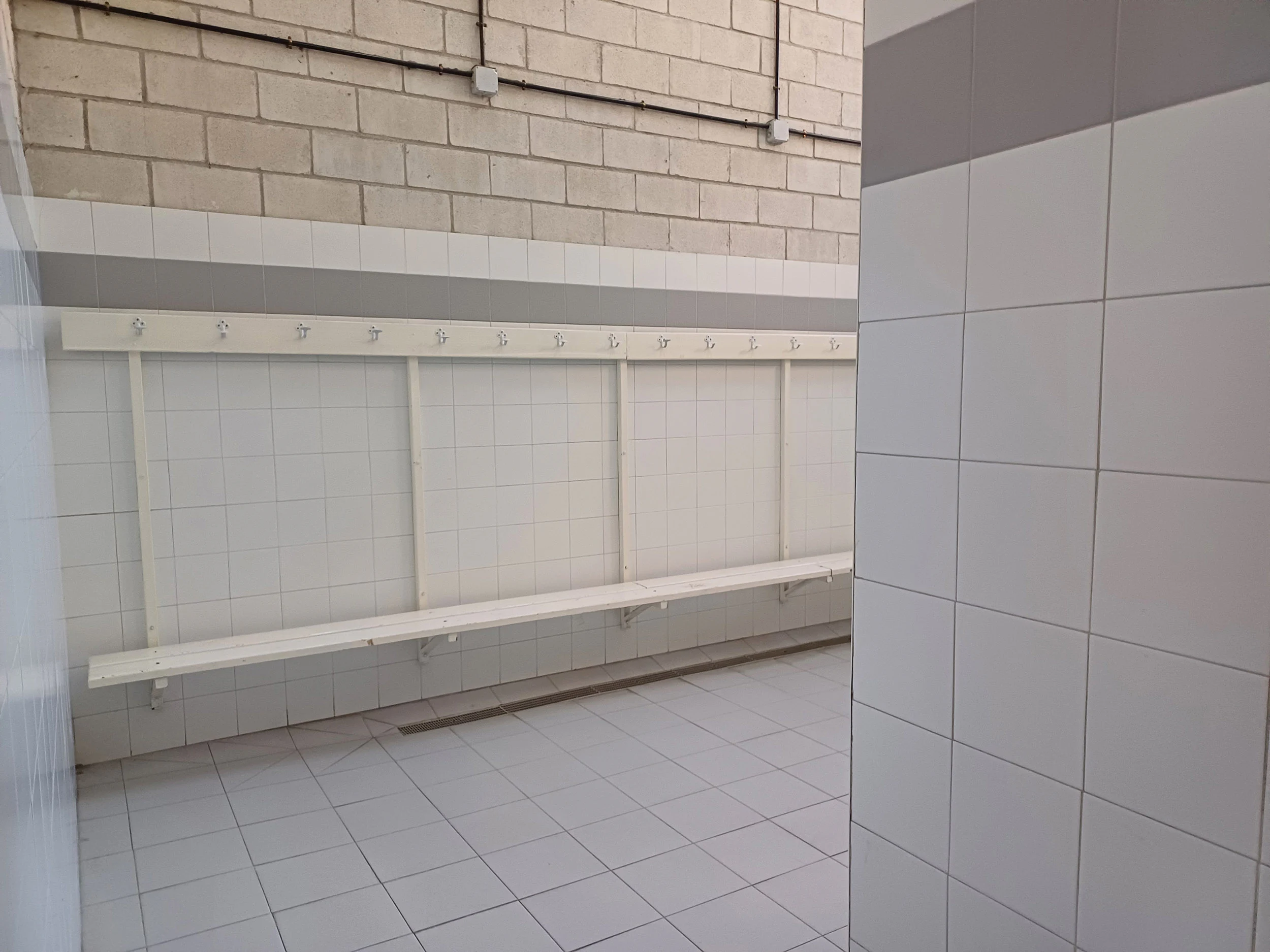 Interior de un vestuario. Perchas en una pared y un banco
