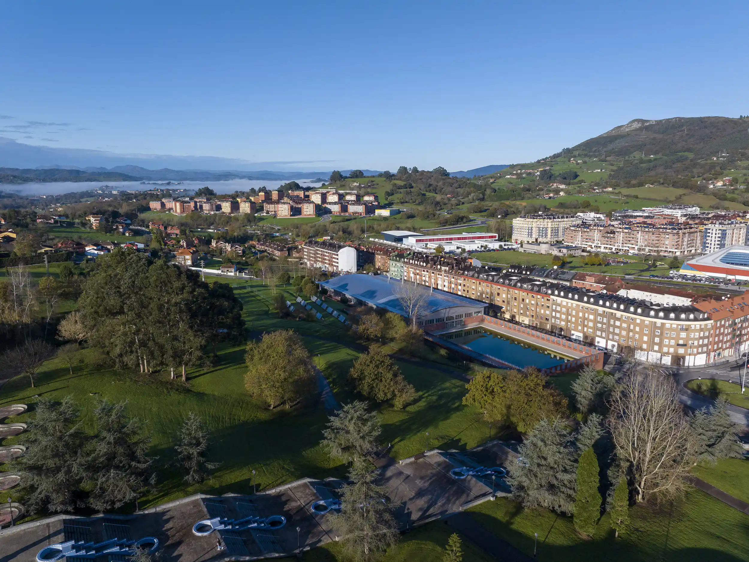 Vista aérea lejana de las piscinas del Parque del Oeste, con el parque y los edificios que las circundan