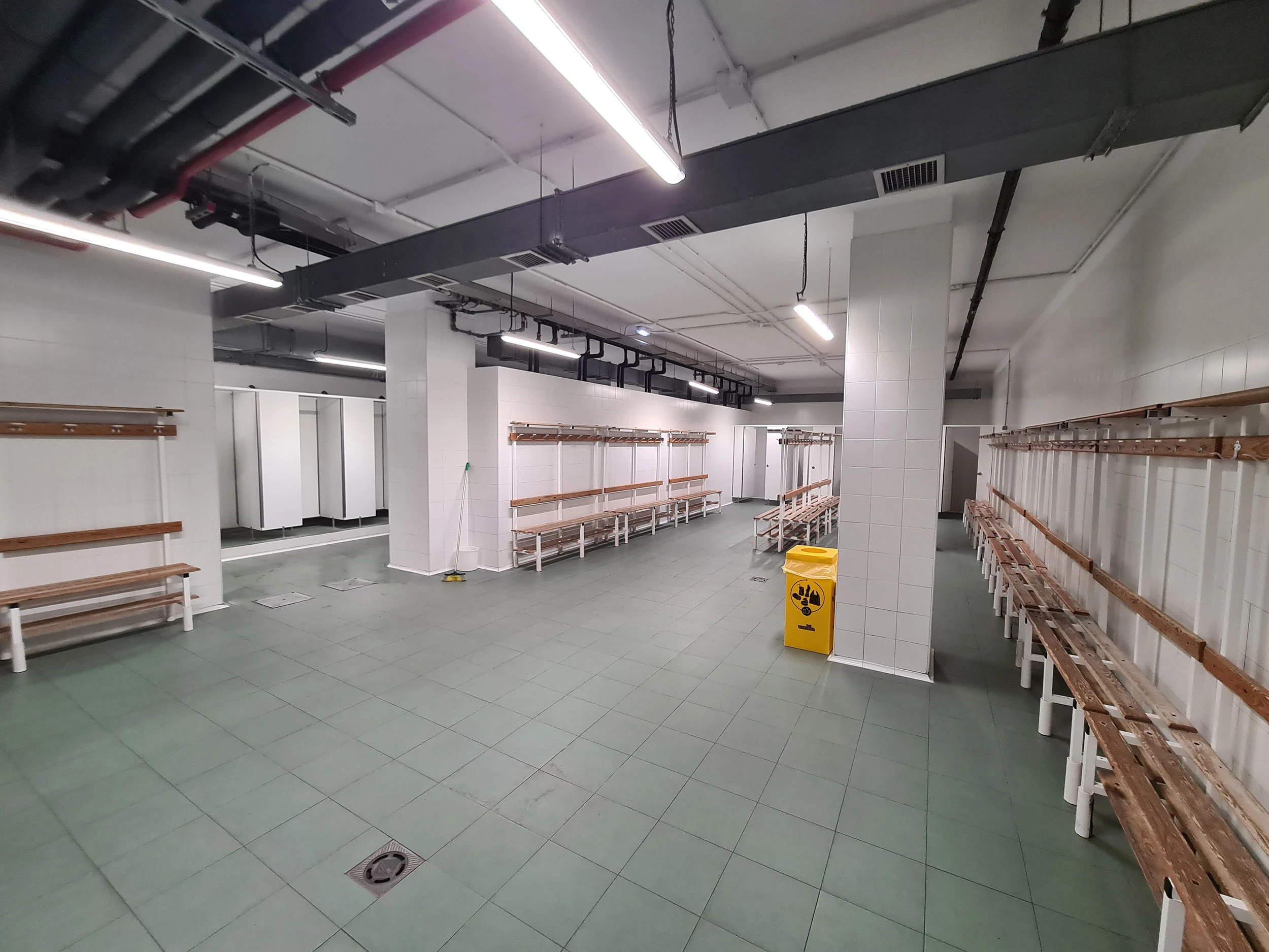 Interior de los vestuarios, con bancos de madera con perchas adosados a las paredes
