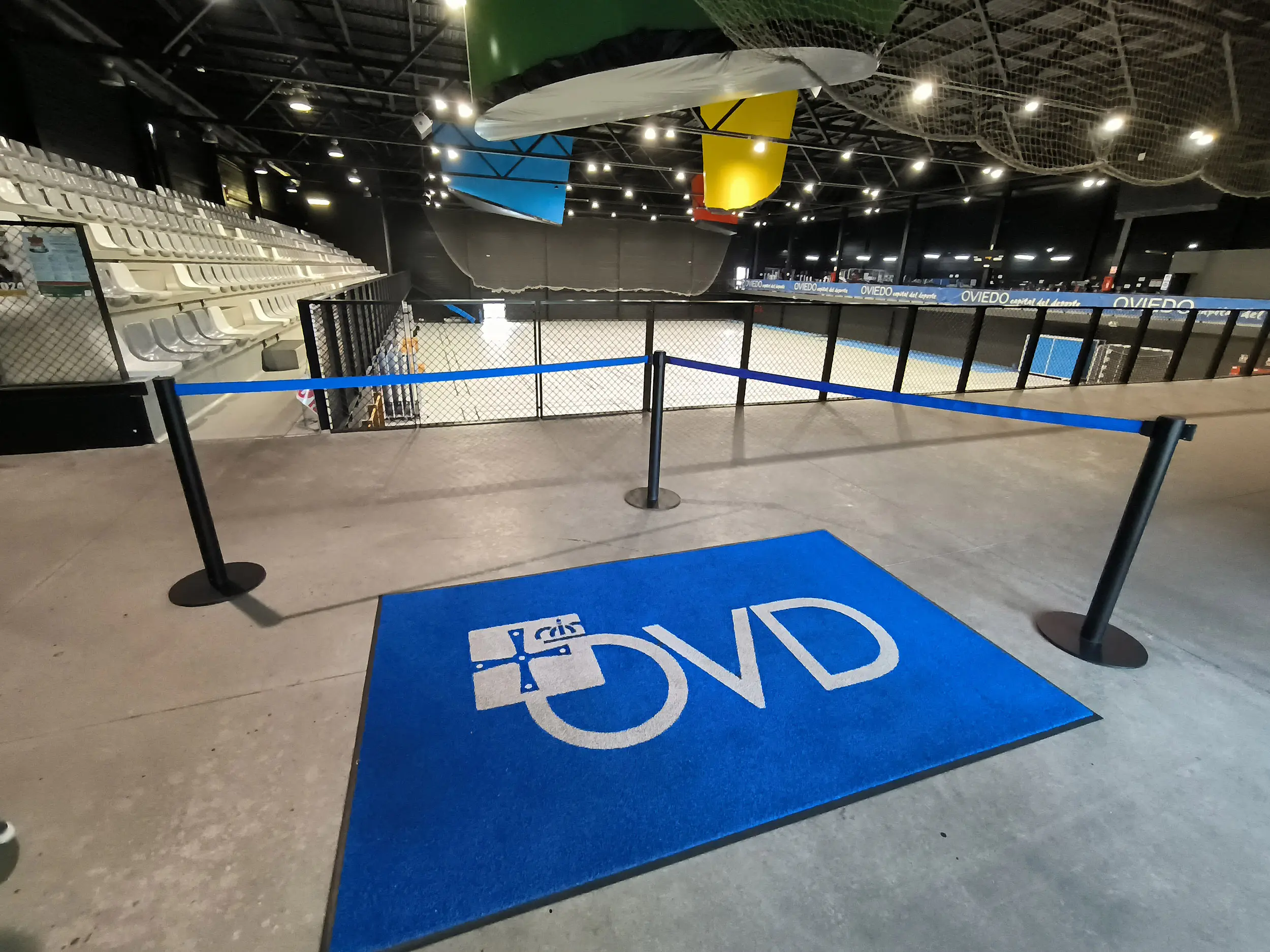 Vista de la zona de gradas y la pista polideportiva. En primer plano, lfombra azul con logotipo del ayuntamiento de Oviedo