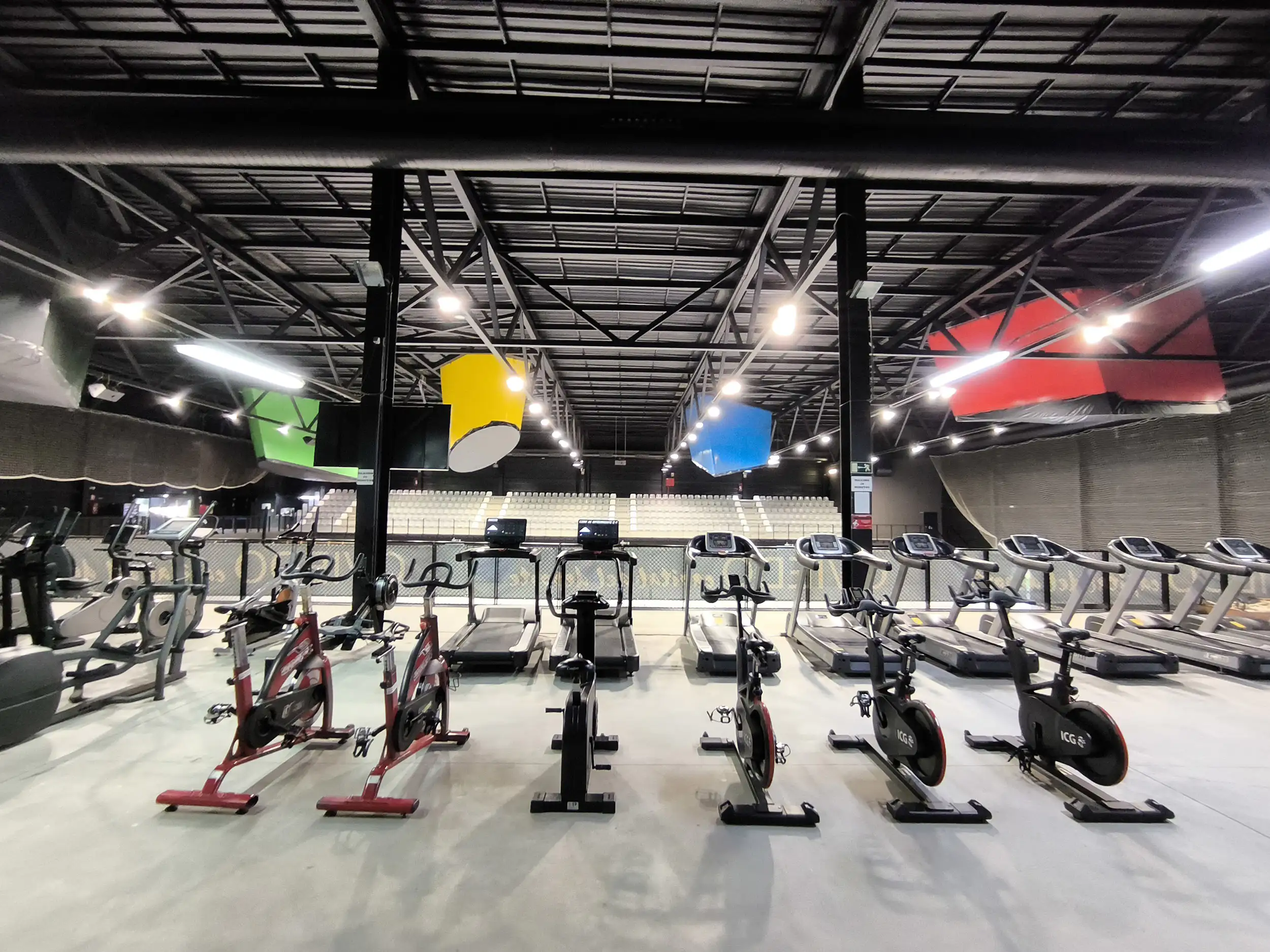 Sala polivalente 2, con bicicletas estáticas y cintas para correr. Al fondo, las gradas de la pista polideportiva