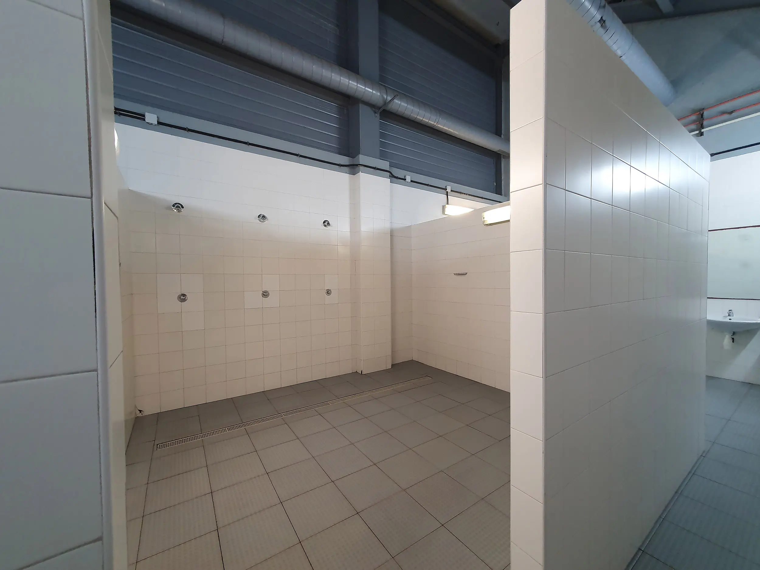 Vestuario azulejado, con una zona de duchas y aseos