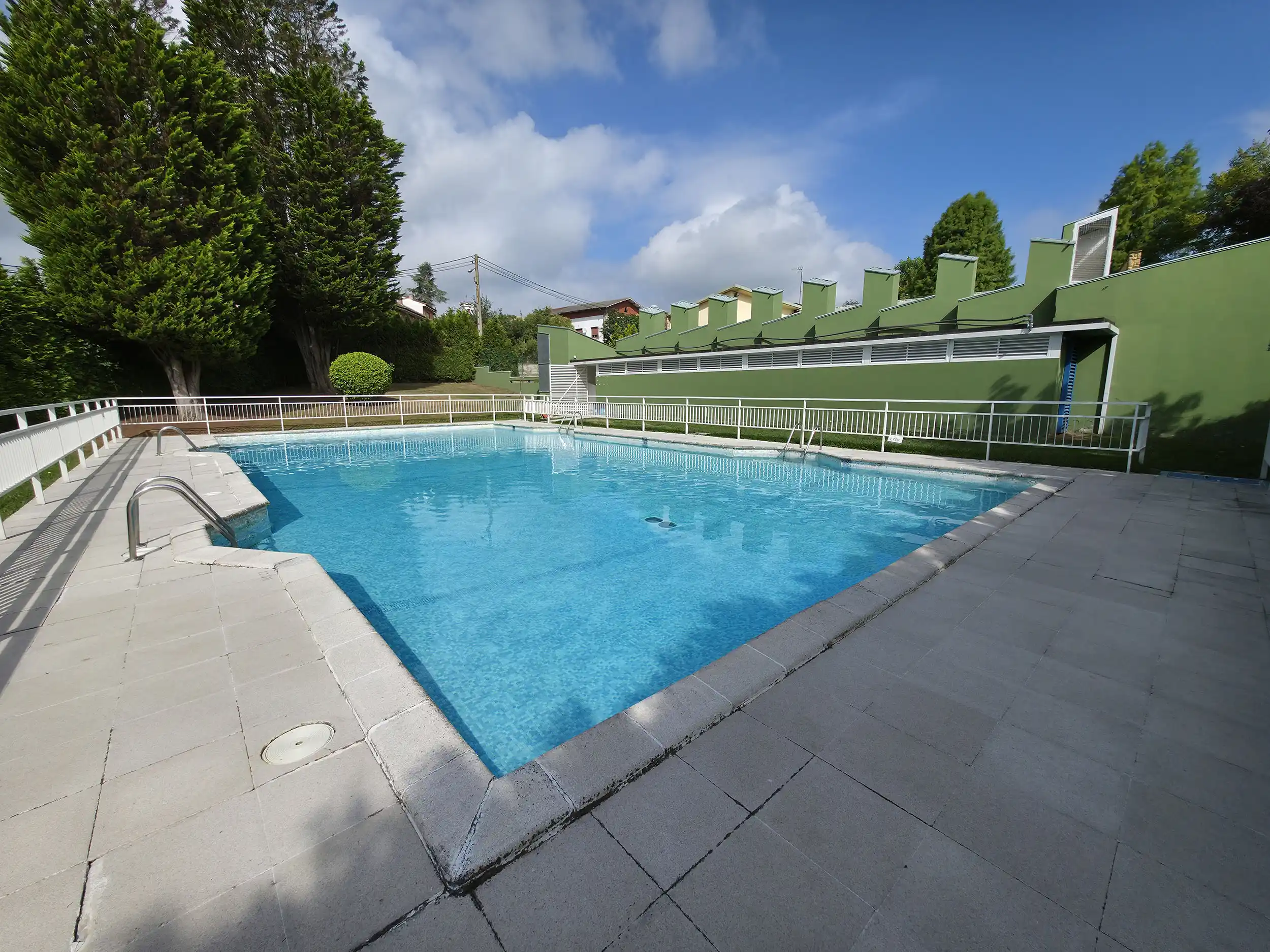 vista de la piscina desde una esquina con el edificio de servicios a la derecha