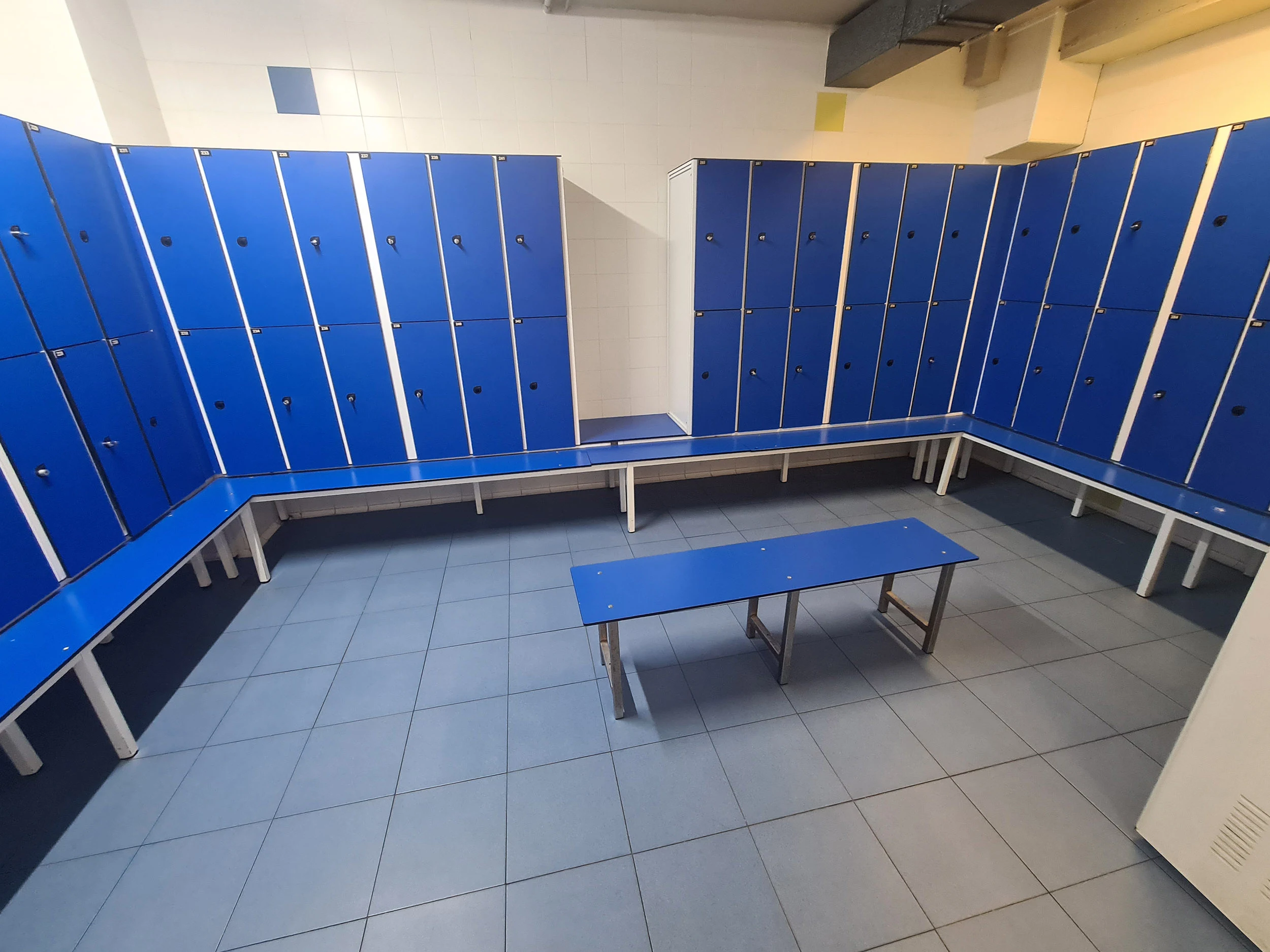 Interior del vestuario, con vista de las taquillas y un banco