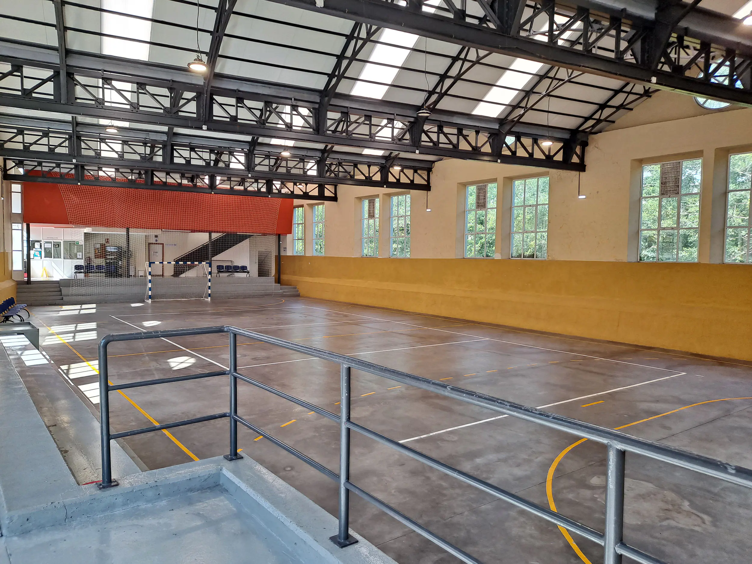 Pista polideportiva con la recepción y entrada al fondo. Zona para publico en primer plano