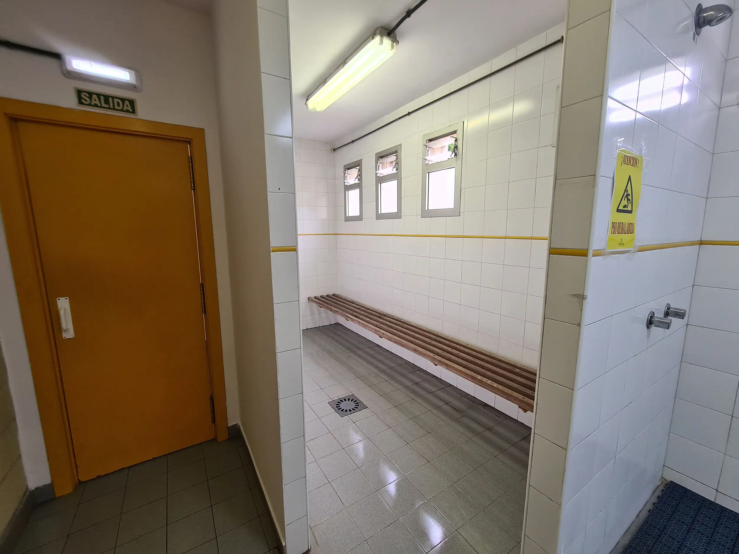 Vista de las duchas y puerta de salida de un vestuario