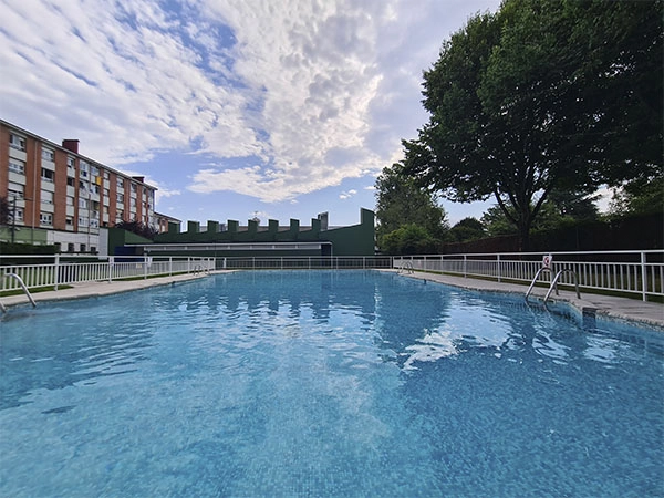 vista de la piscina desde un fondo, con edificio de servicios al fondo