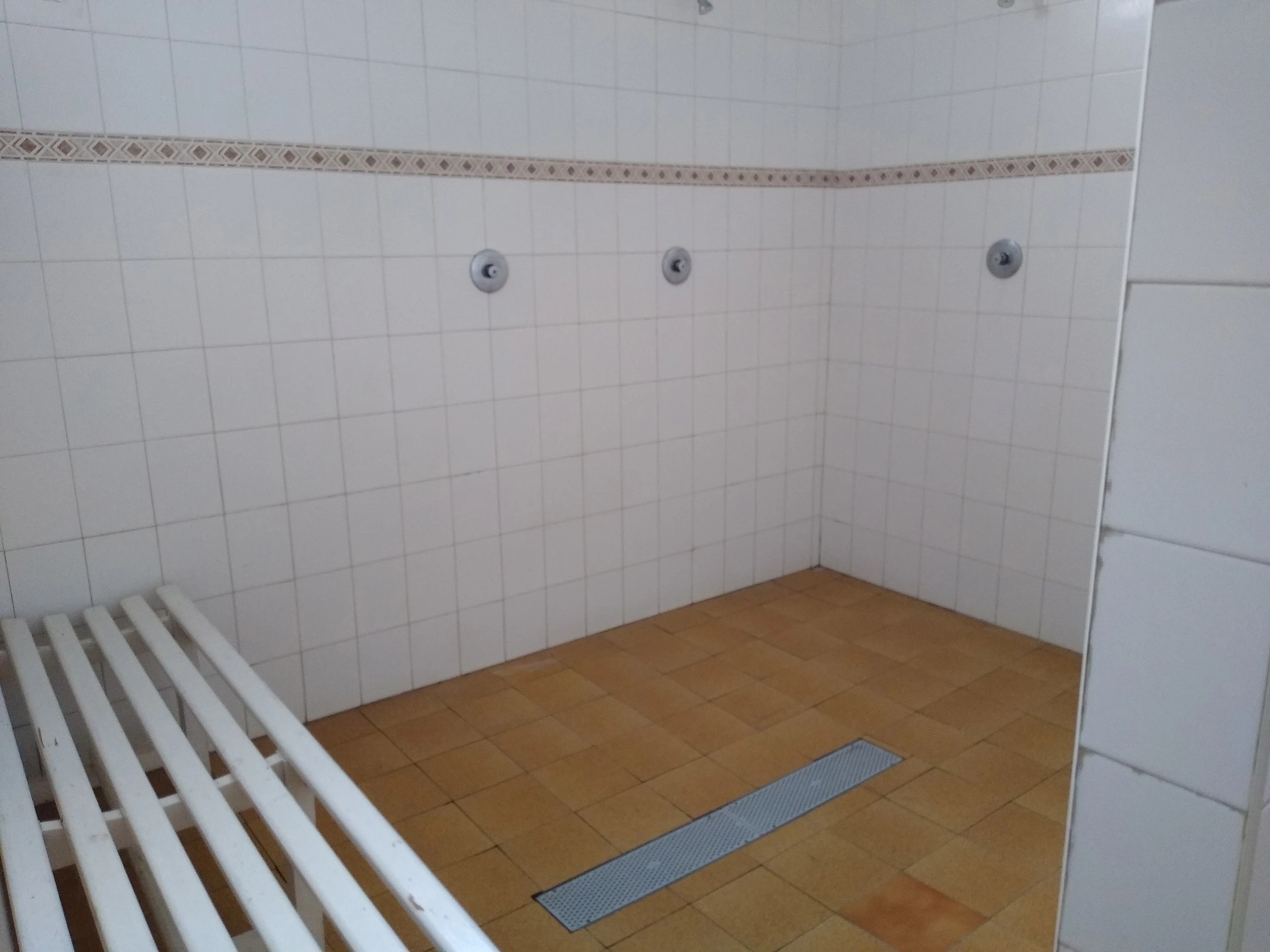 Sala de duchas con banco y paredes de azulejos