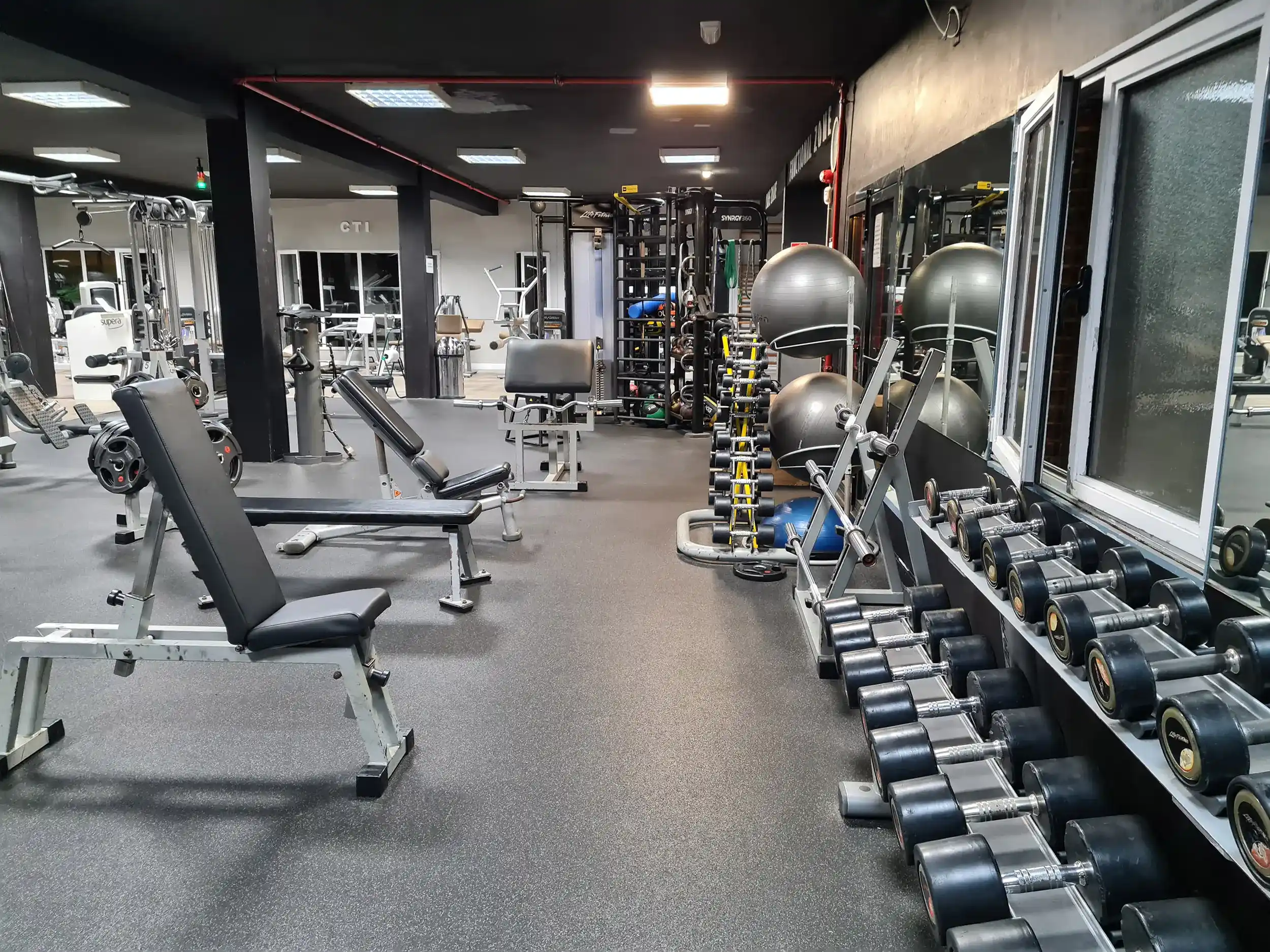 Sala de musculación, con conjunto de mancuernas en sus soportes y bancos de musculación
