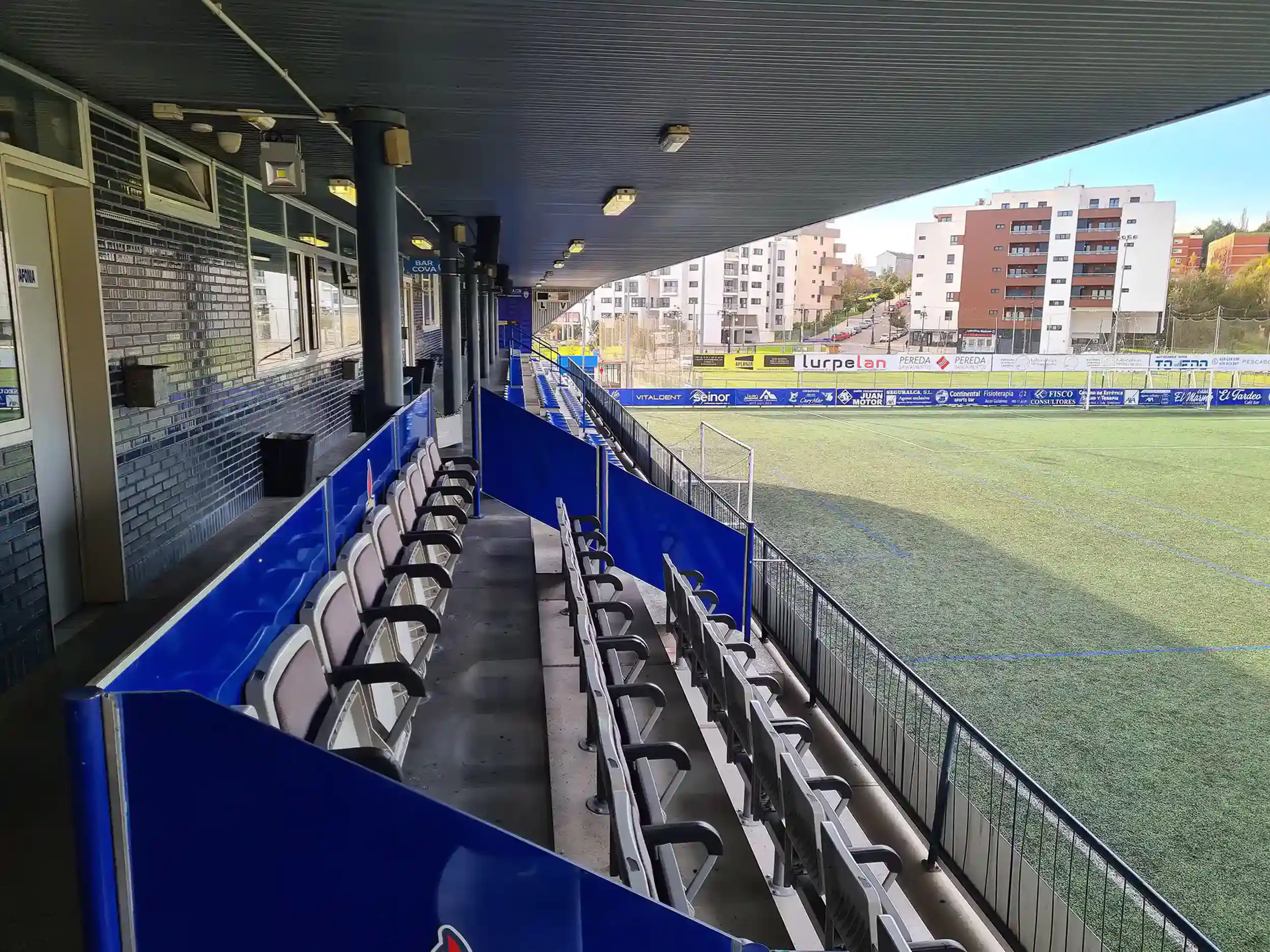 Lateral de la grada cubierta y parte del campo. Las diferentes partes de la grada están separadas por paneles azules