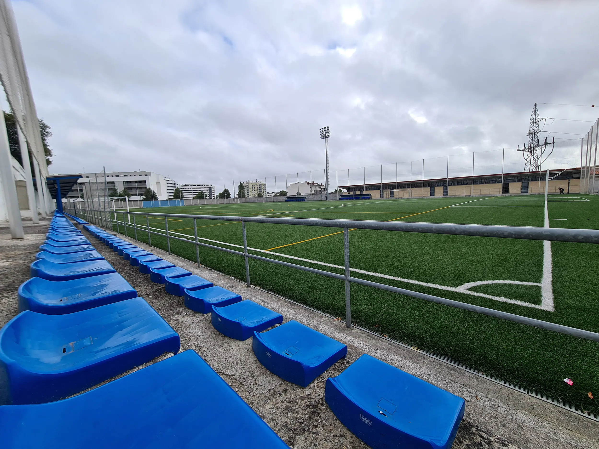 Primer plano de dos filas de asientos azules de las gradas al descubierto del campo de fútbol