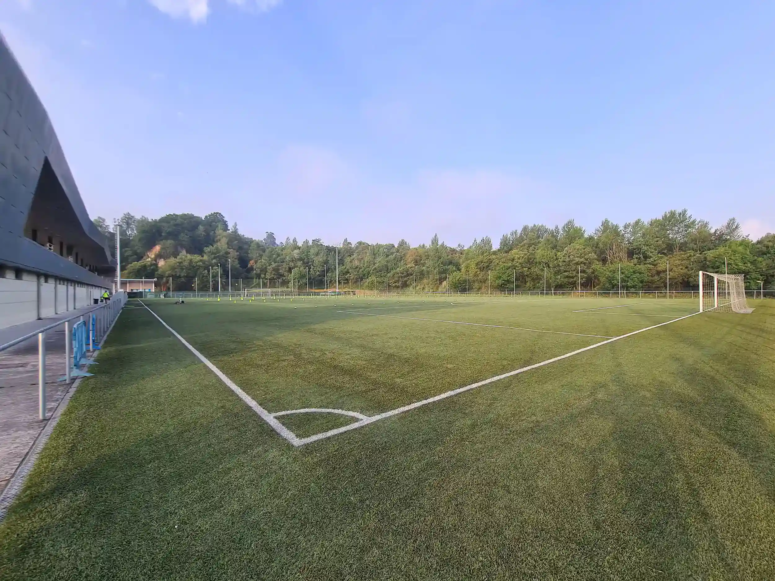 Panorámica de un campo de fútbol 11 desde uno de los córneres, con la portería y una vista parcial de las gradas