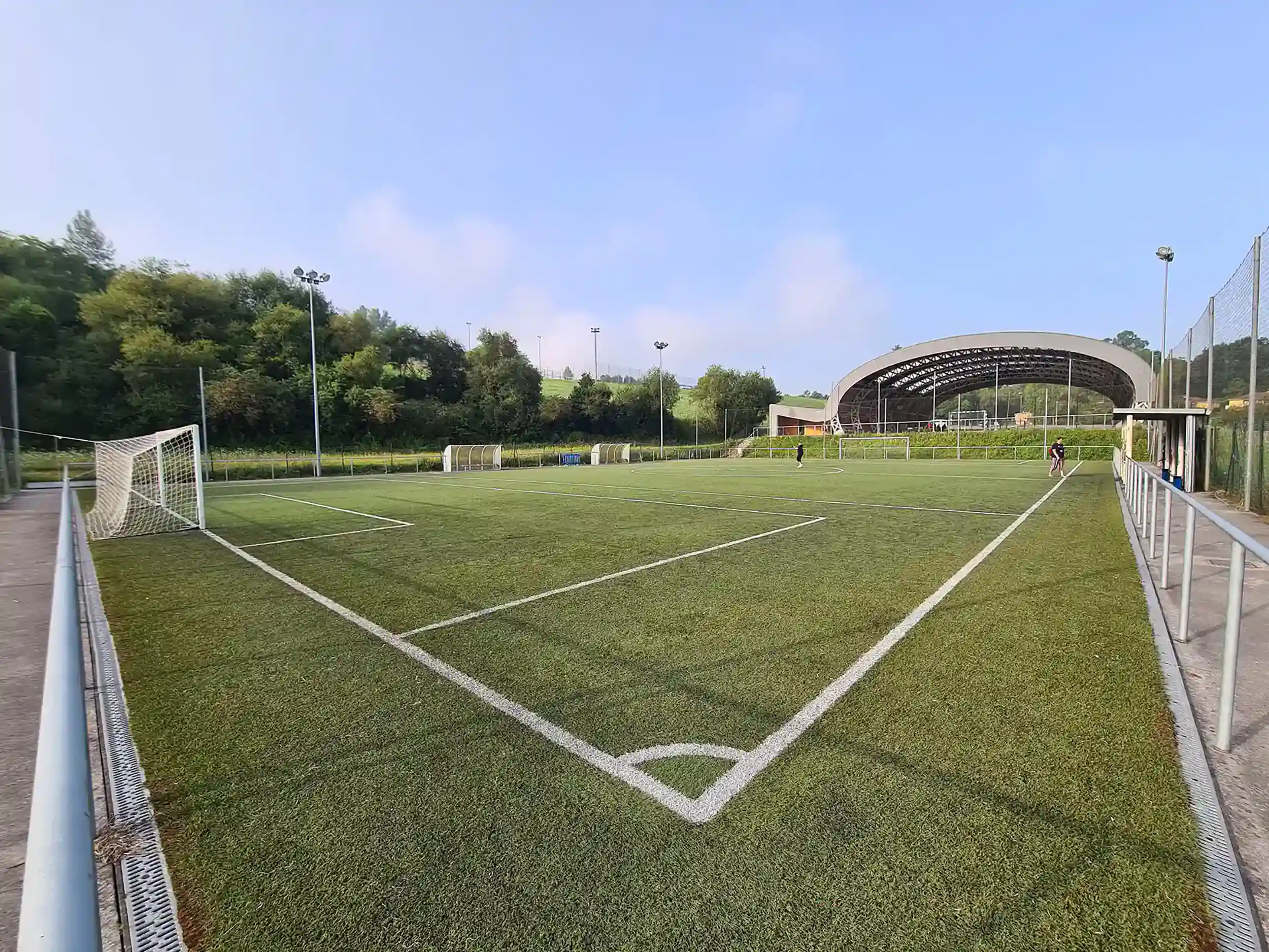Panorámica de uno de los campos de fútbol 8 desde uno de los córneres, con las porterías y la pista polideportiva al fondo
