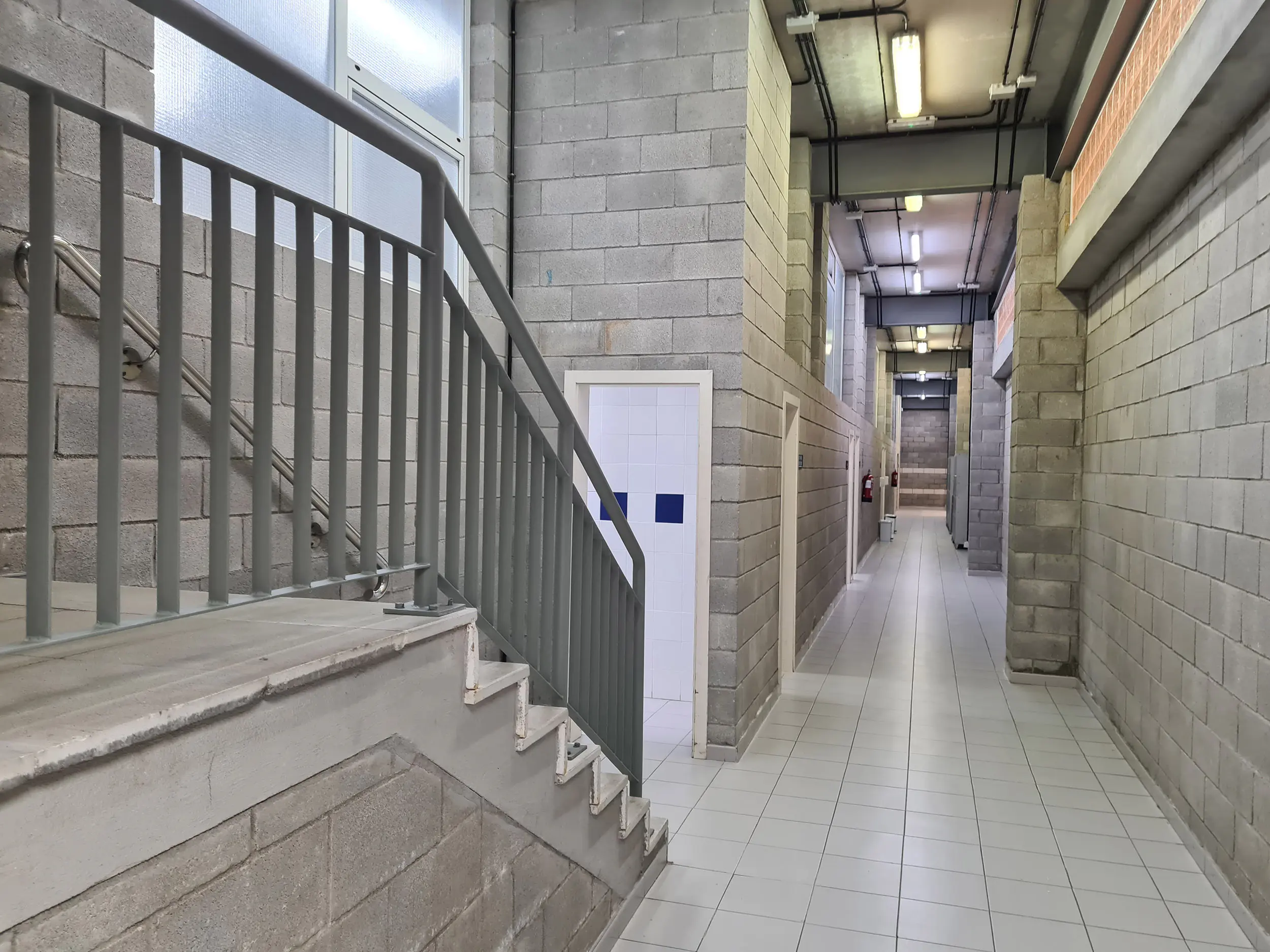 Escalera para subida a planta superior y pasillo de acceso a vestuarios