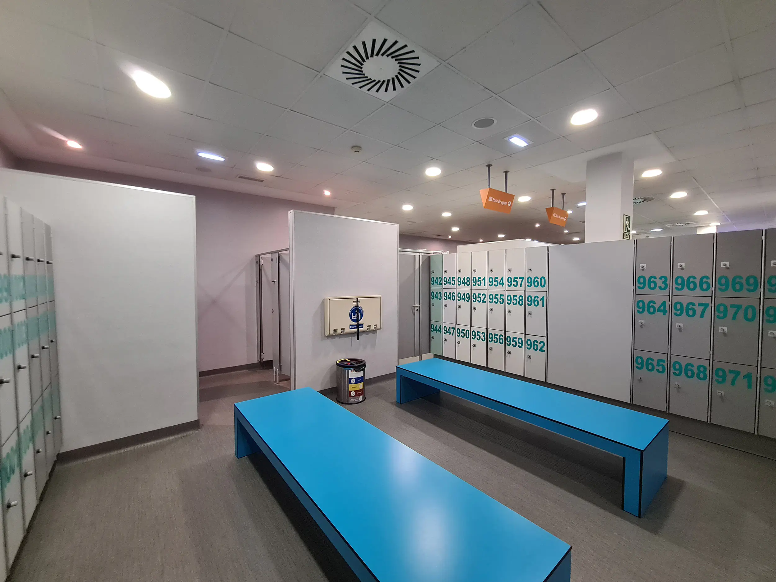 Interior de los vestuarios femeninos, con bancos, taquillas y cambiador de pañales horizontal plegable