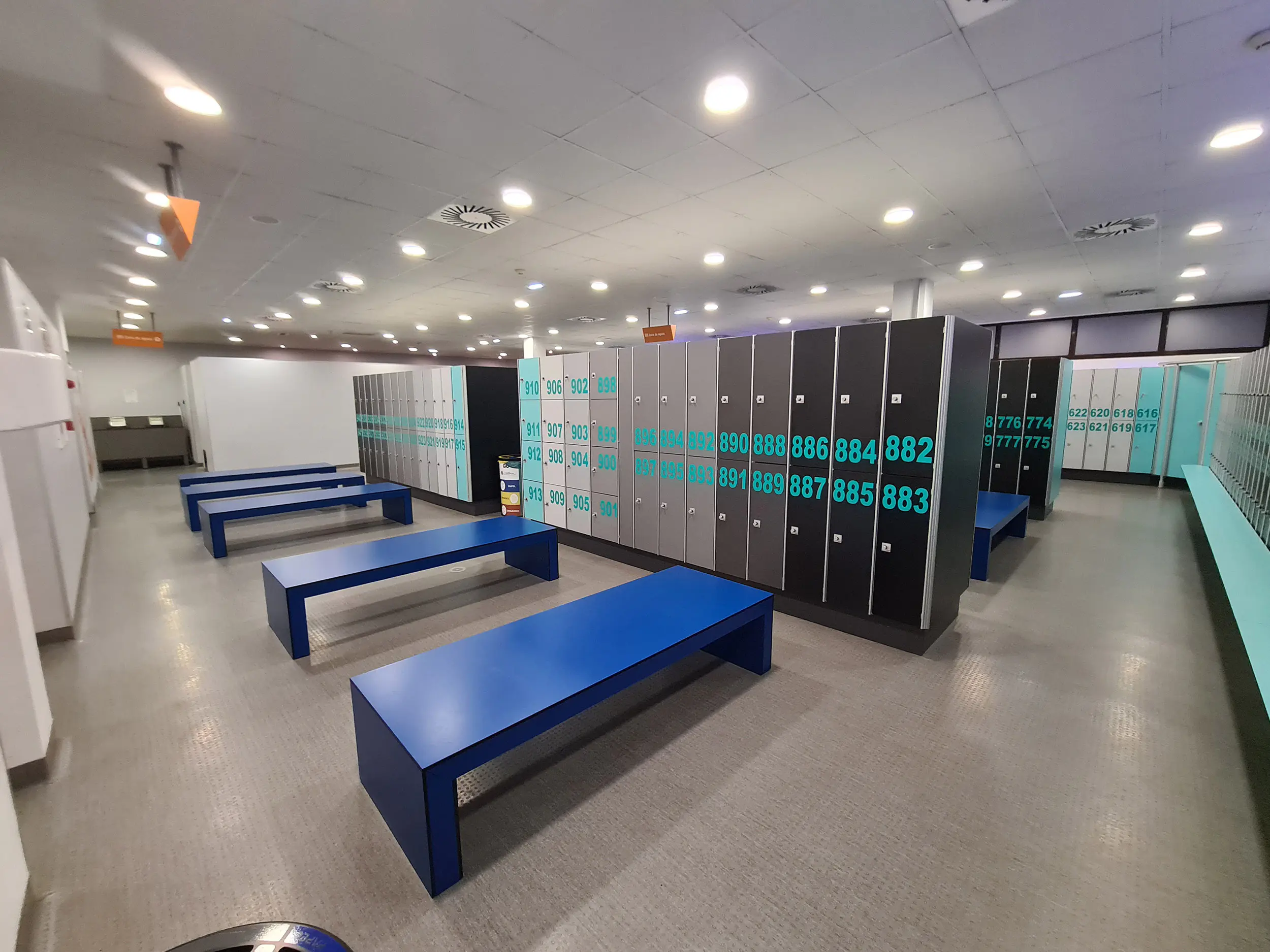 Interior de los vestuarios masculinos, con bancos y taquillas