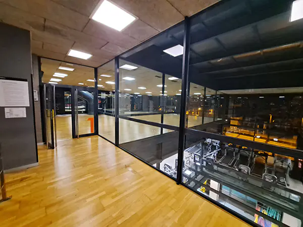 Acceso a una de las salas de actividades dirigidas, con vista parcial de la sala de fitness del piso inferior