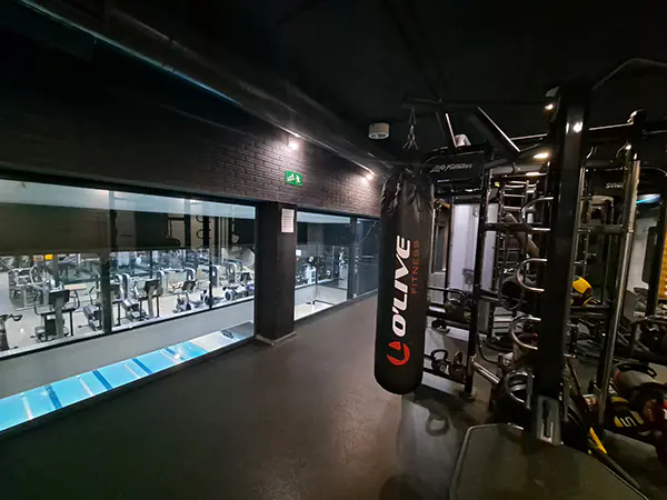 Sala de fitness, con máquina de musculación en primer plano y otras máquinas deportivas al fondo