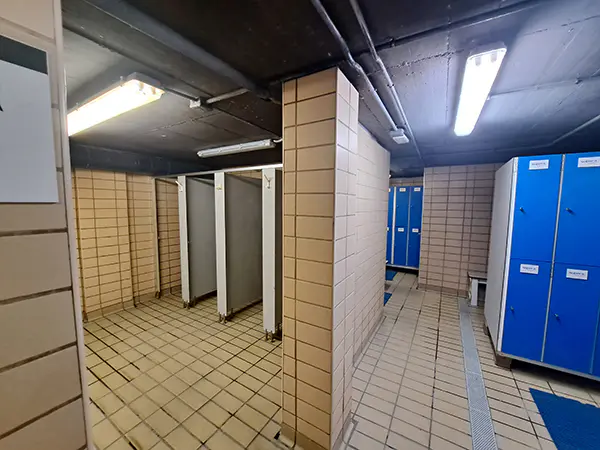 Interior del vestuario masculino, con vista parcial de las taquillas y las duchas