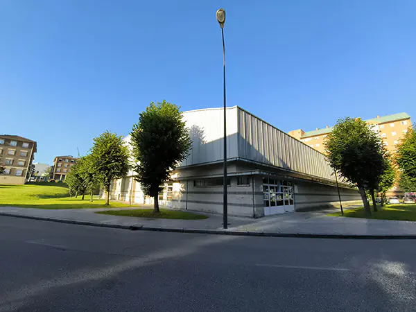 Edificio del polideportivo, tomado desde zona verde aledaña. Al fondo de la imagen aparece un edificio de viviendas 