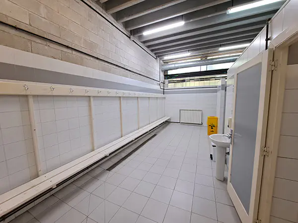 Uno de los vestuarios. Fila de bancos, lavabo y acceso a las duchas