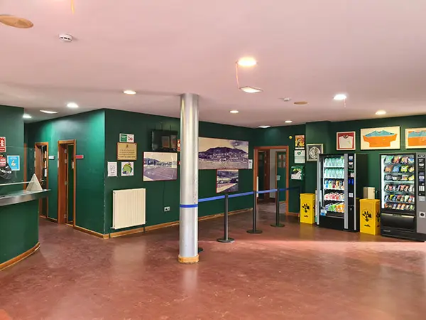 Área de recepción, con el mostrador a la izquierda, máquinas expendedoras a la derecha y accesos al interior