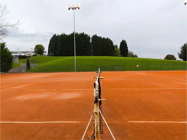 Lateral de una pista de tenis de tierra batida, con detalle de la red