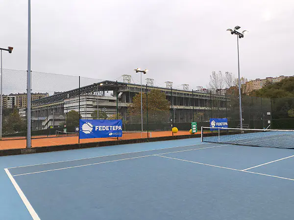Pista de tenis de green set descubierta, con el Estadio Carlos Tartiere, al fondo