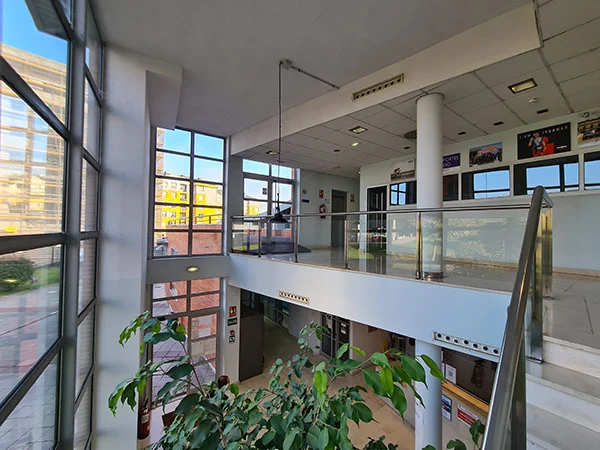 Vestíbulo de entrada desde las escaleras de acceso al segundo piso, con vista en detalle de los grandes ventanales